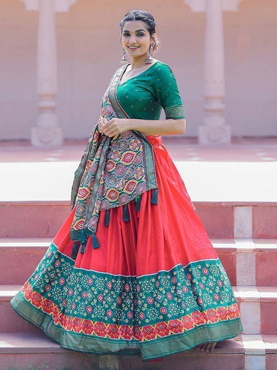 Woman in vibrant red and green lehenga choli with embroidered dupatta, perfect for Indian ethnic occasions.