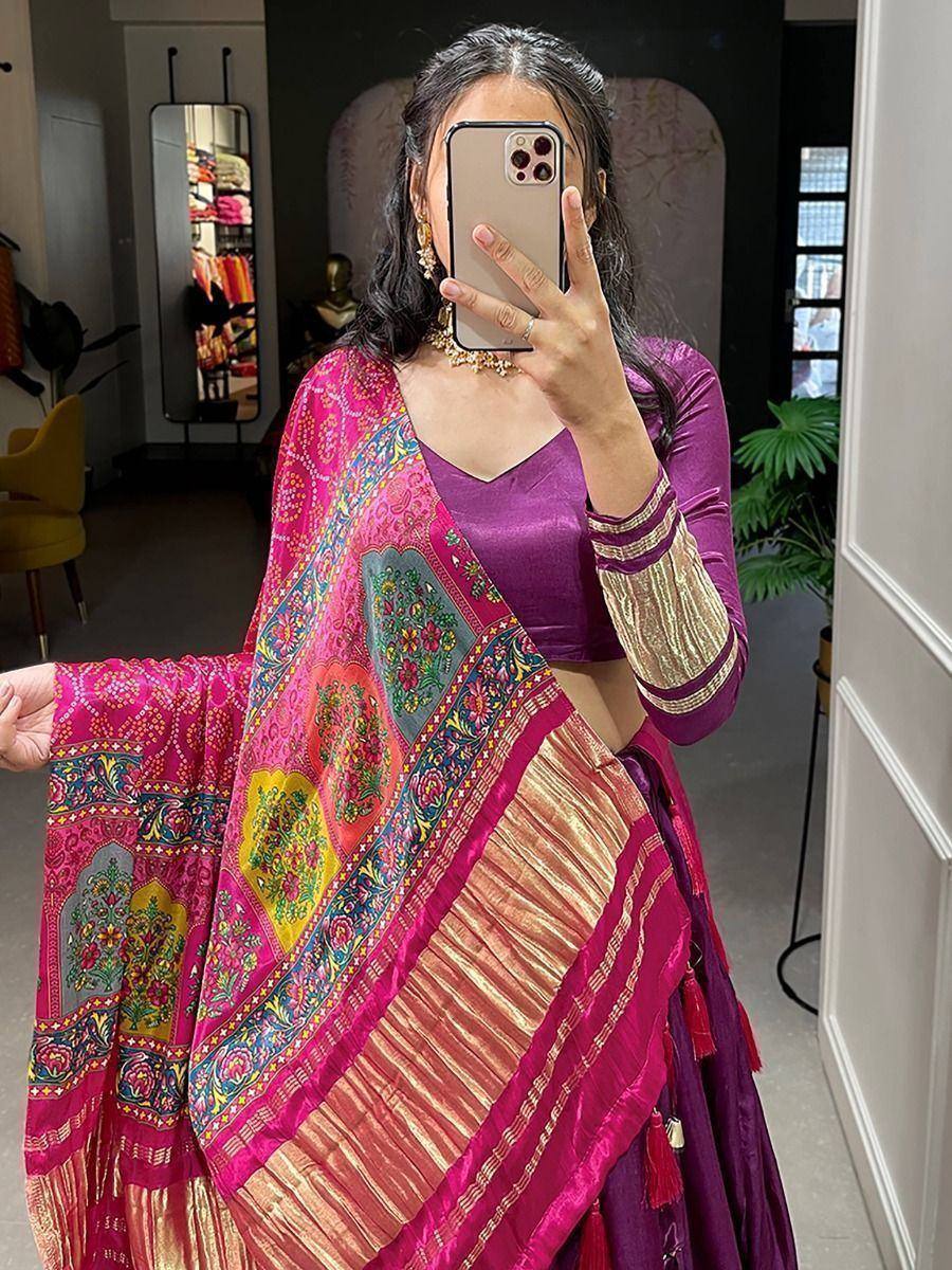 Woman in vibrant pink and purple ethnic lehenga choli with embroidered dupatta, taking mirror selfie