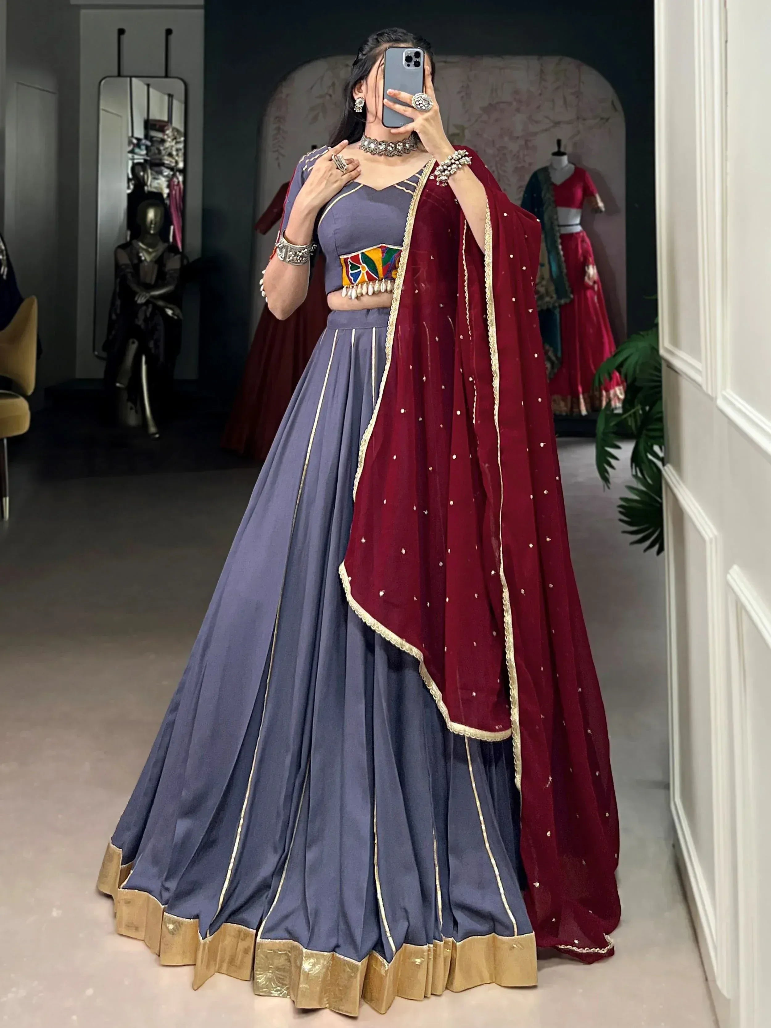 Purple lehenga choli with maroon dupatta, gold trim, and mirror work, perfect for Indian ethnic wear events.