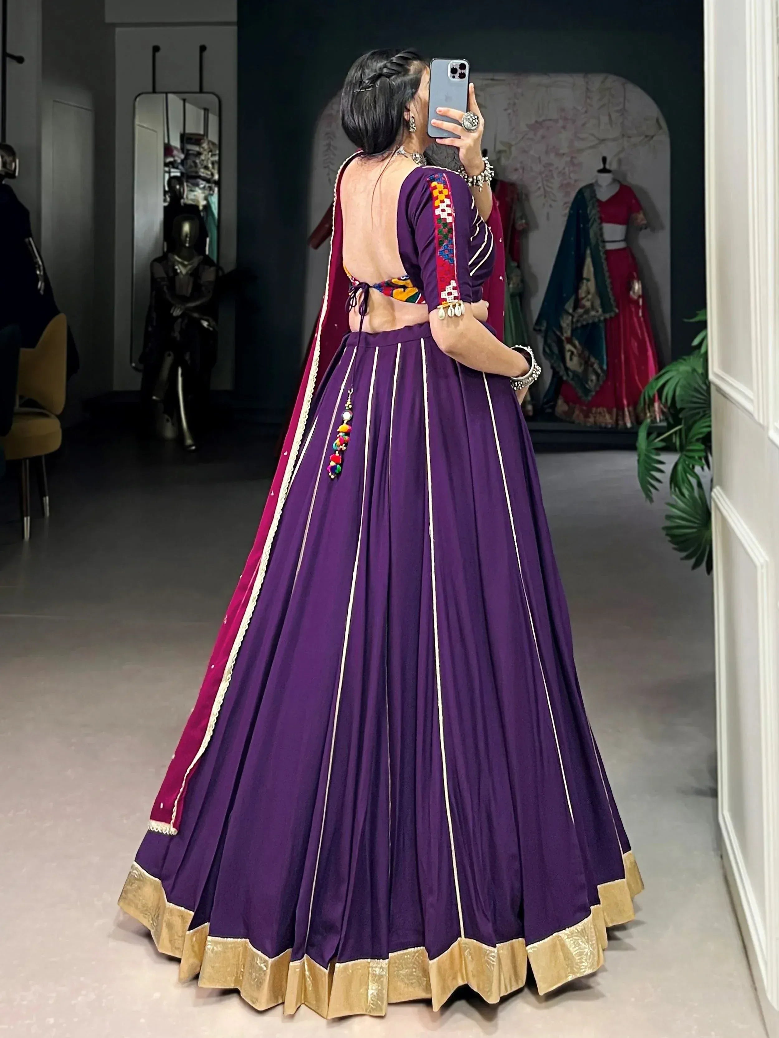Purple designer lehenga choli with backless blouse, gold trim, and colorful embroidery, perfect for Indian ethnic wear.