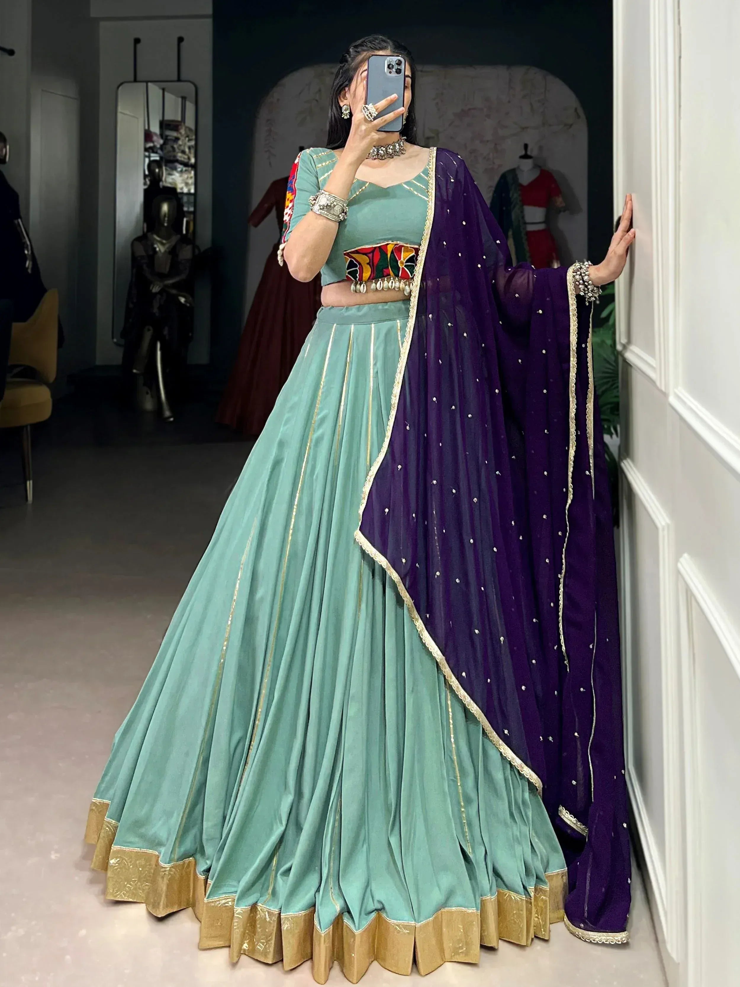 Teal lehenga choli with purple dupatta, gold trim, and embroidered waistband for ethnic wear