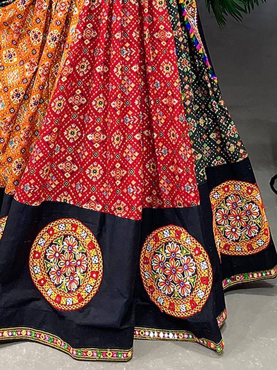 Vibrant ethnic lehenga with red, orange, and black panels, floral mirror work, and intricate geometric prints.