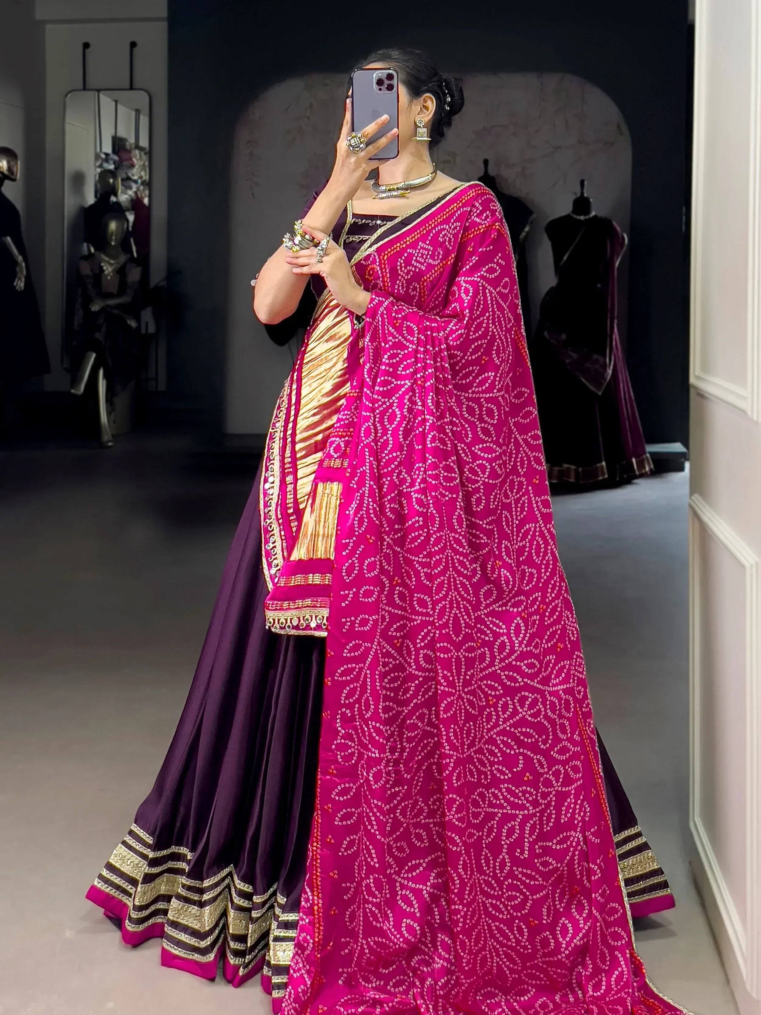 Woman in vibrant pink and purple designer lehenga choli with intricate embroidery, perfect for Indian ethnic wear.