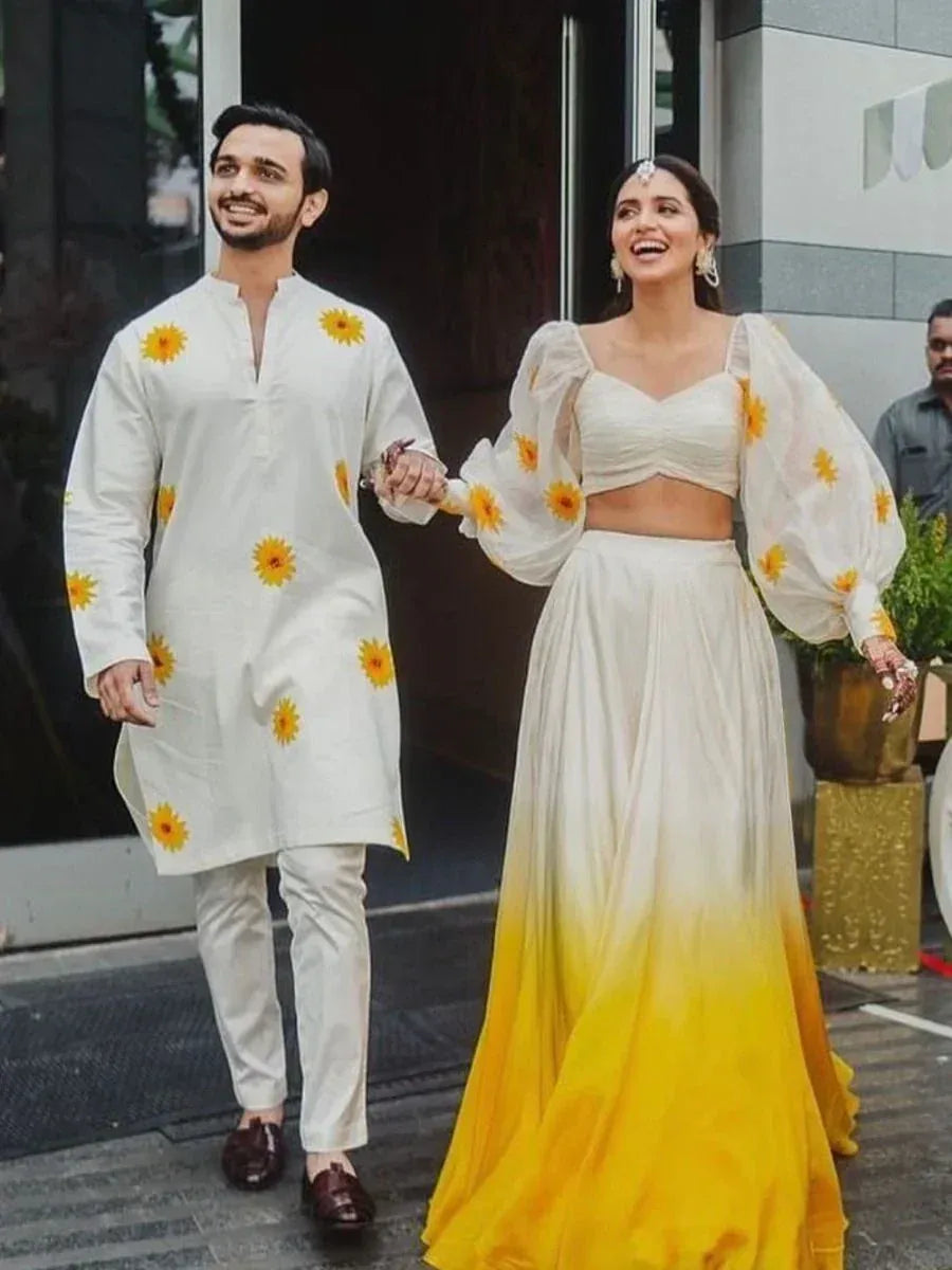 Couple in matching white and yellow floral ethnic wear, woman in ombre lehenga choli, man in kurta set