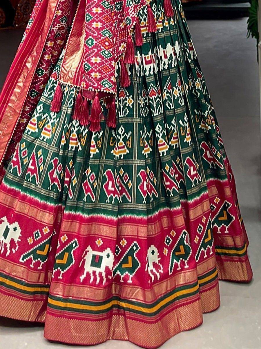 Green and pink ethnic lehenga with folk art print and tassels, perfect for Indian weddings and festivals.