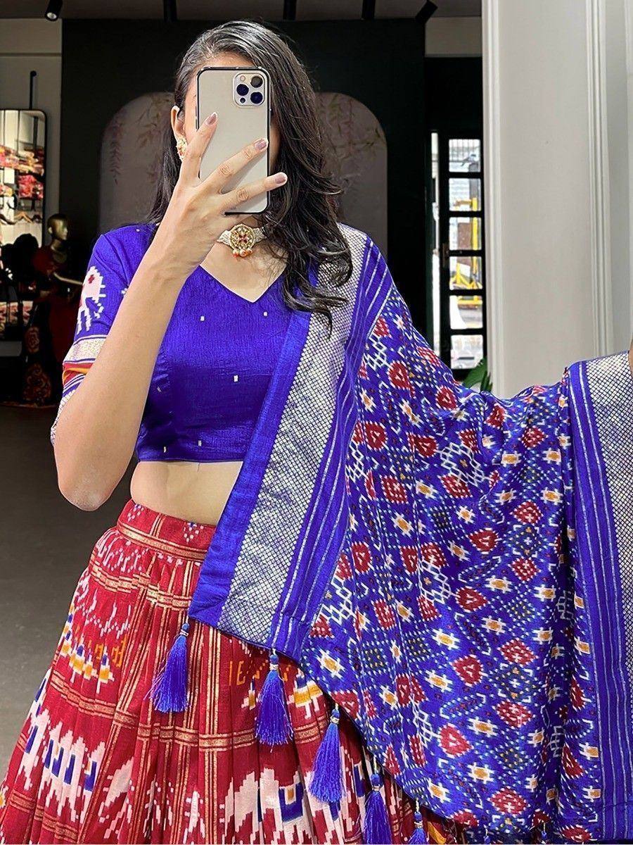 Woman in vibrant blue and red Ikat lehenga choli with matching dupatta, perfect for ethnic occasions