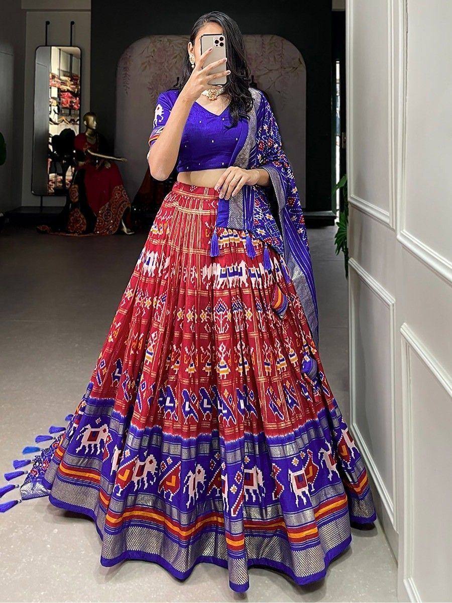 Woman in vibrant red and blue printed lehenga choli with ethnic motifs, perfect for Indian festive occasions