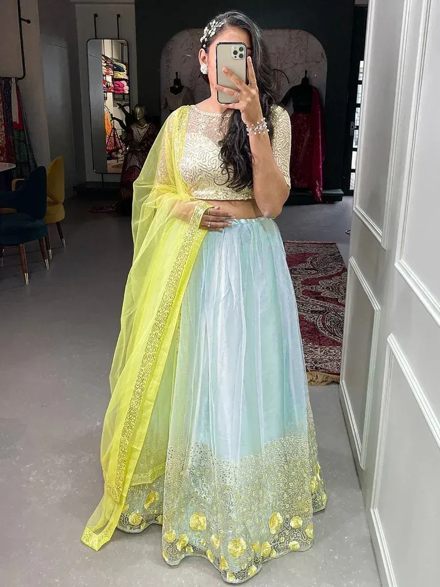 Woman in yellow and mint green lehenga choli with floral embroidery, perfect for Indian ethnic occasions