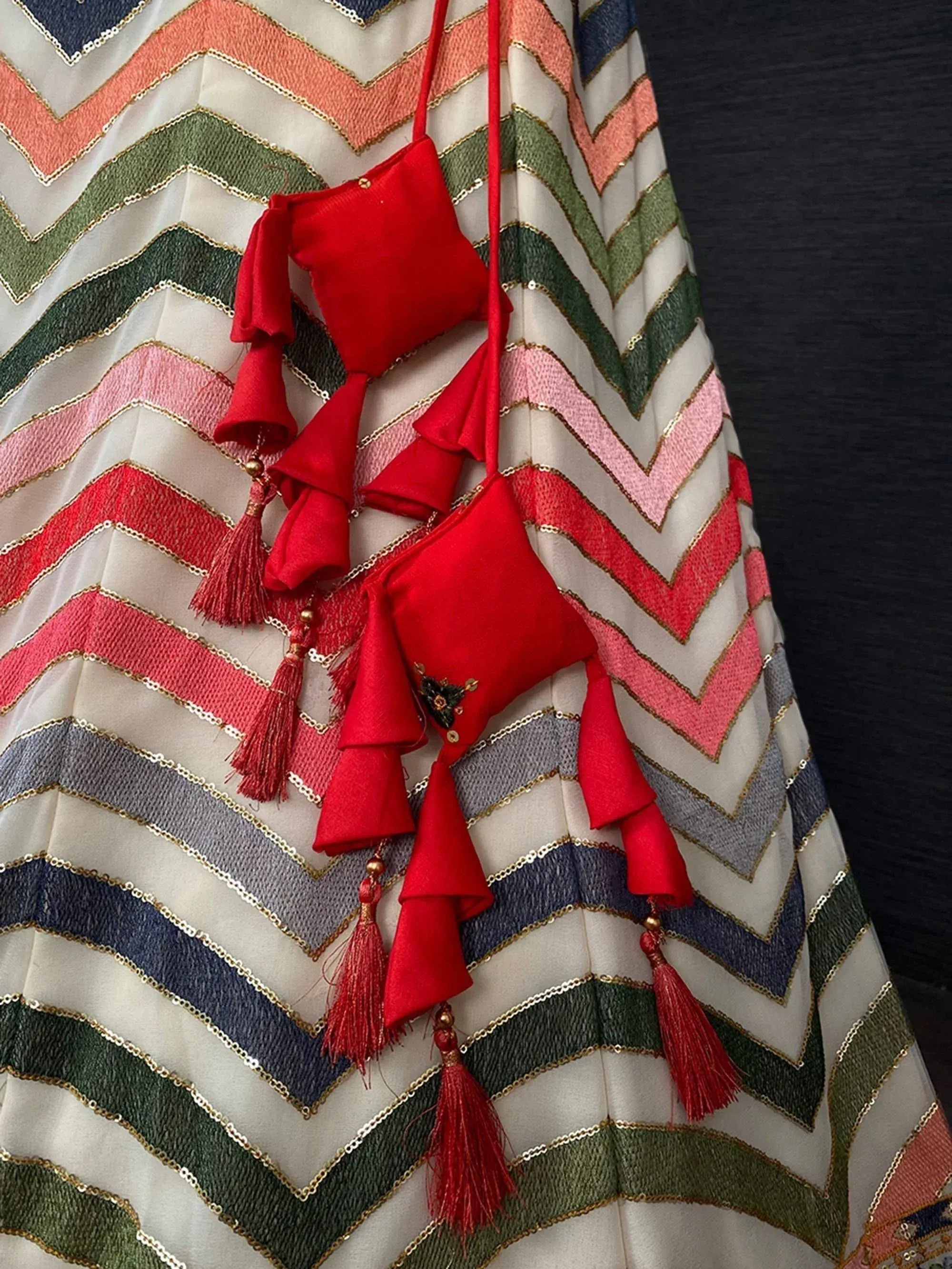 Red tassel pouches on colorful chevron embroidered lehenga skirt, ethnic Indian wear