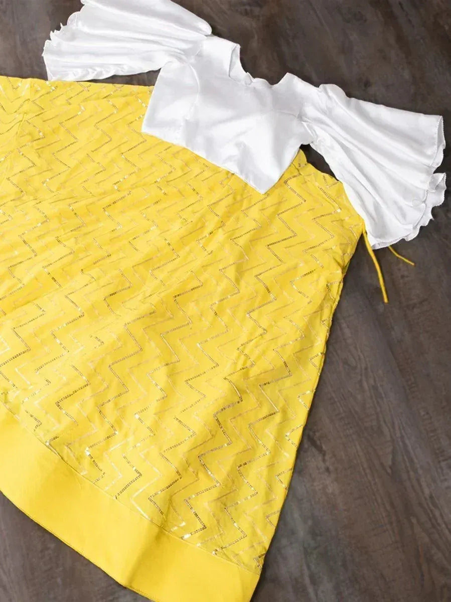 Yellow ethnic gown with silver zigzag embroidery and white ruffled sleeves, perfect for festive occasions.