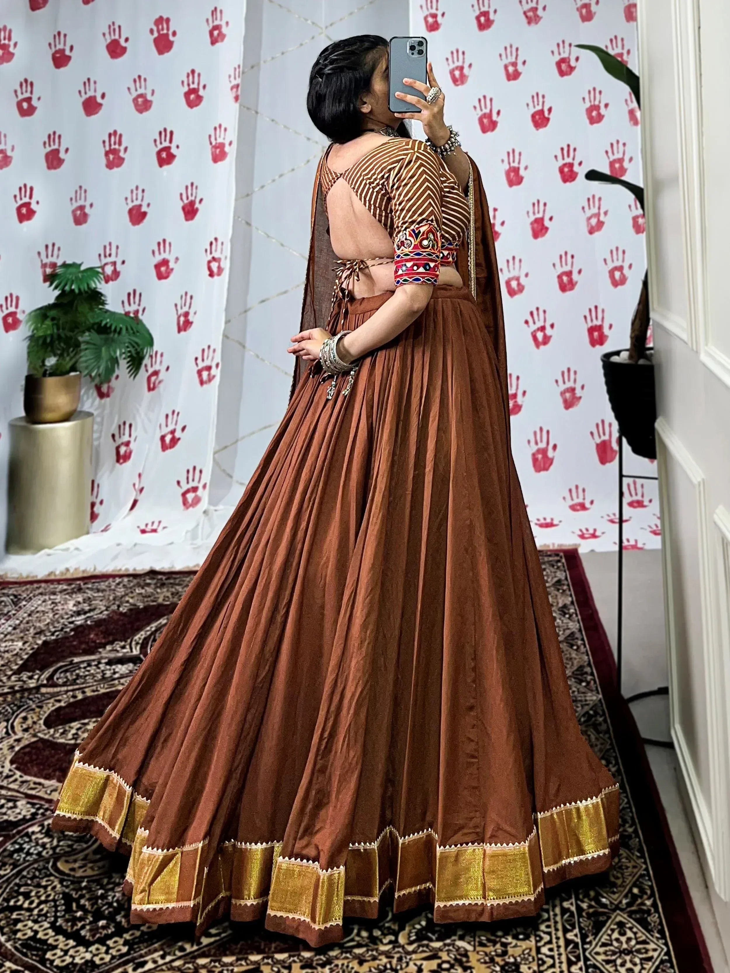 Brown ethnic lehenga choli with gold border, mirror work blouse, and pleated skirt for Indian wear