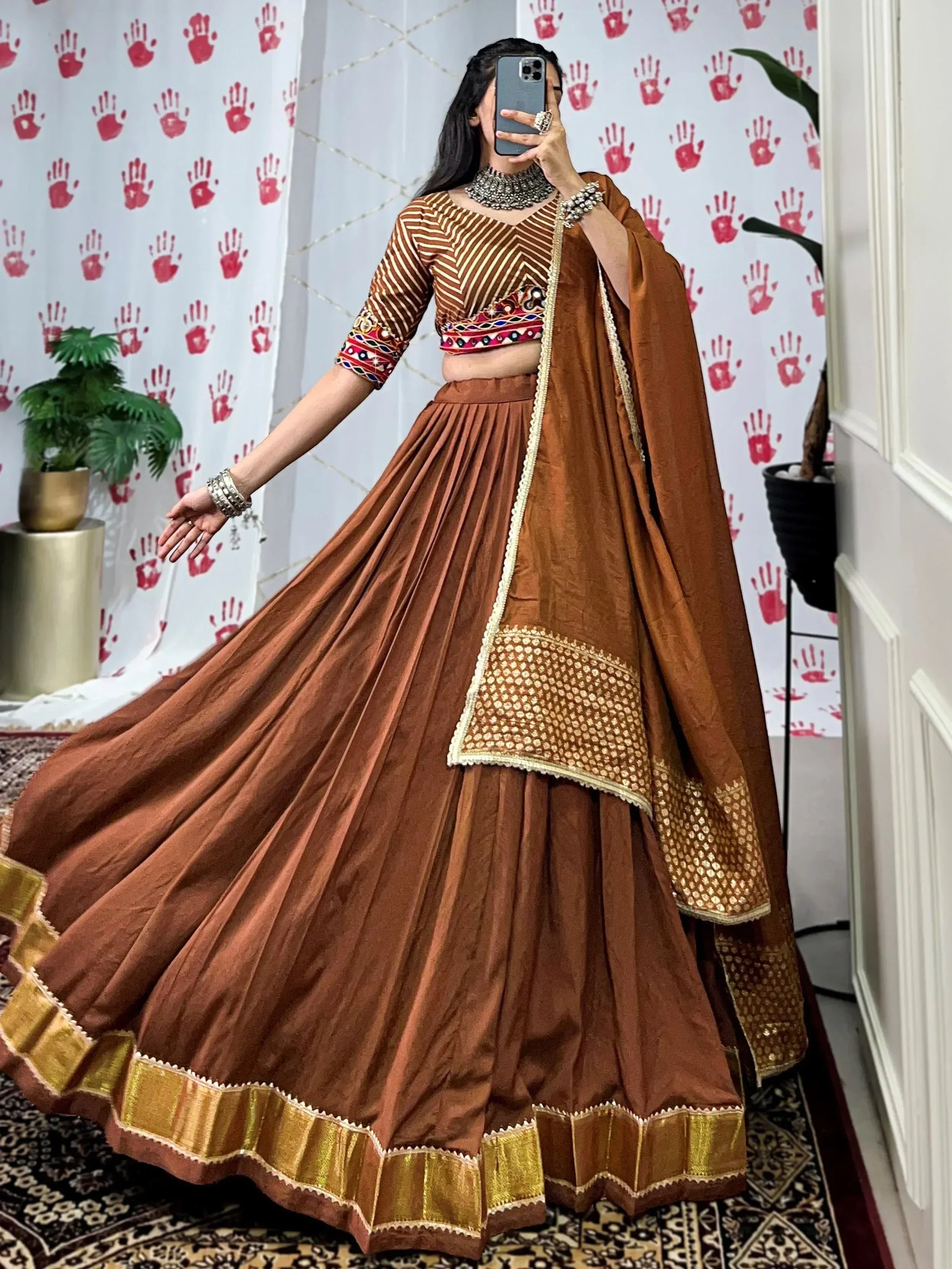 Brown ethnic lehenga choli with gold trim, mirror work blouse, and dupatta for Indian weddings or festivals