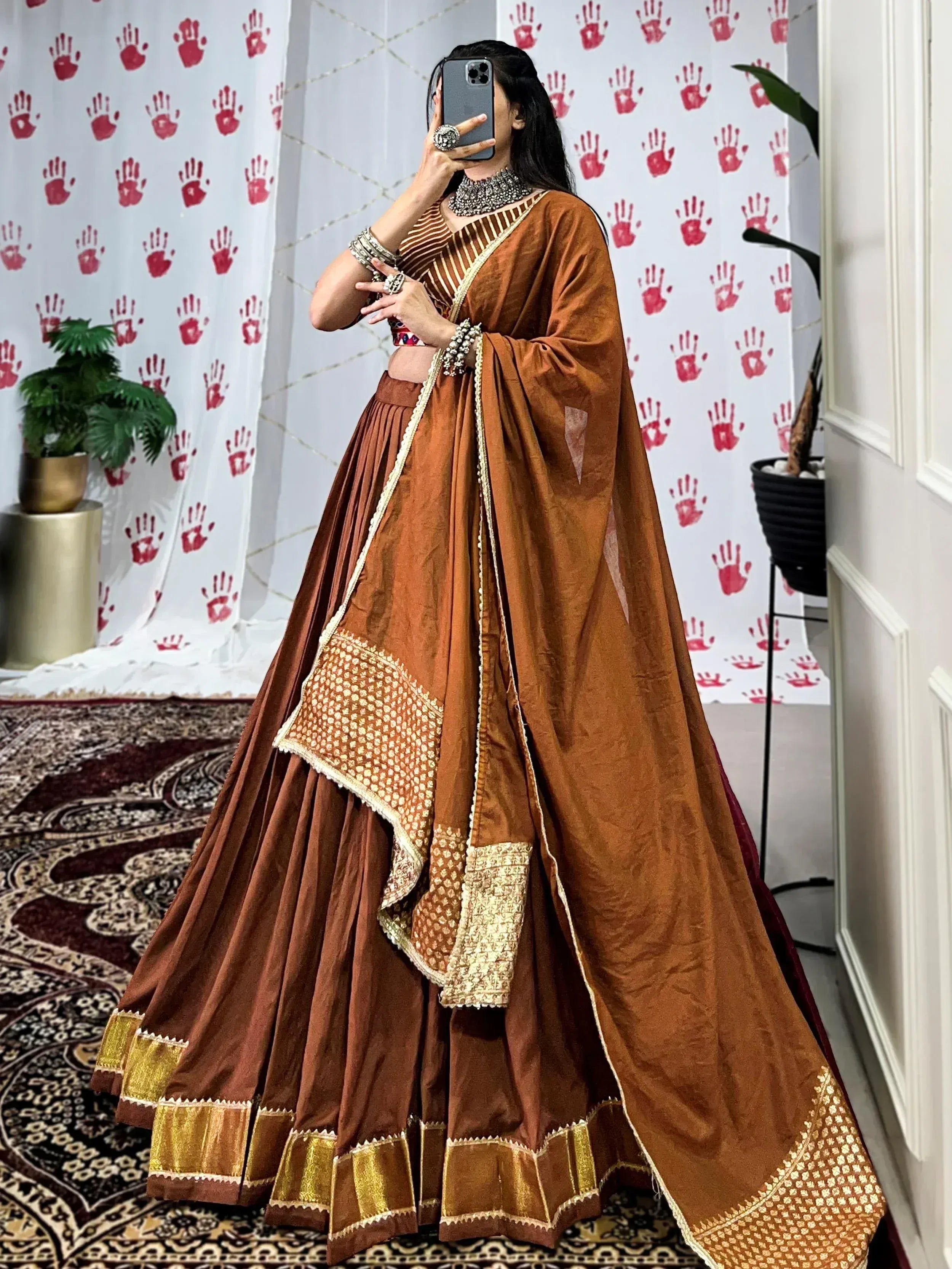 Woman in rust brown designer lehenga choli with gold embroidery, perfect for Indian ethnic wear occasions.