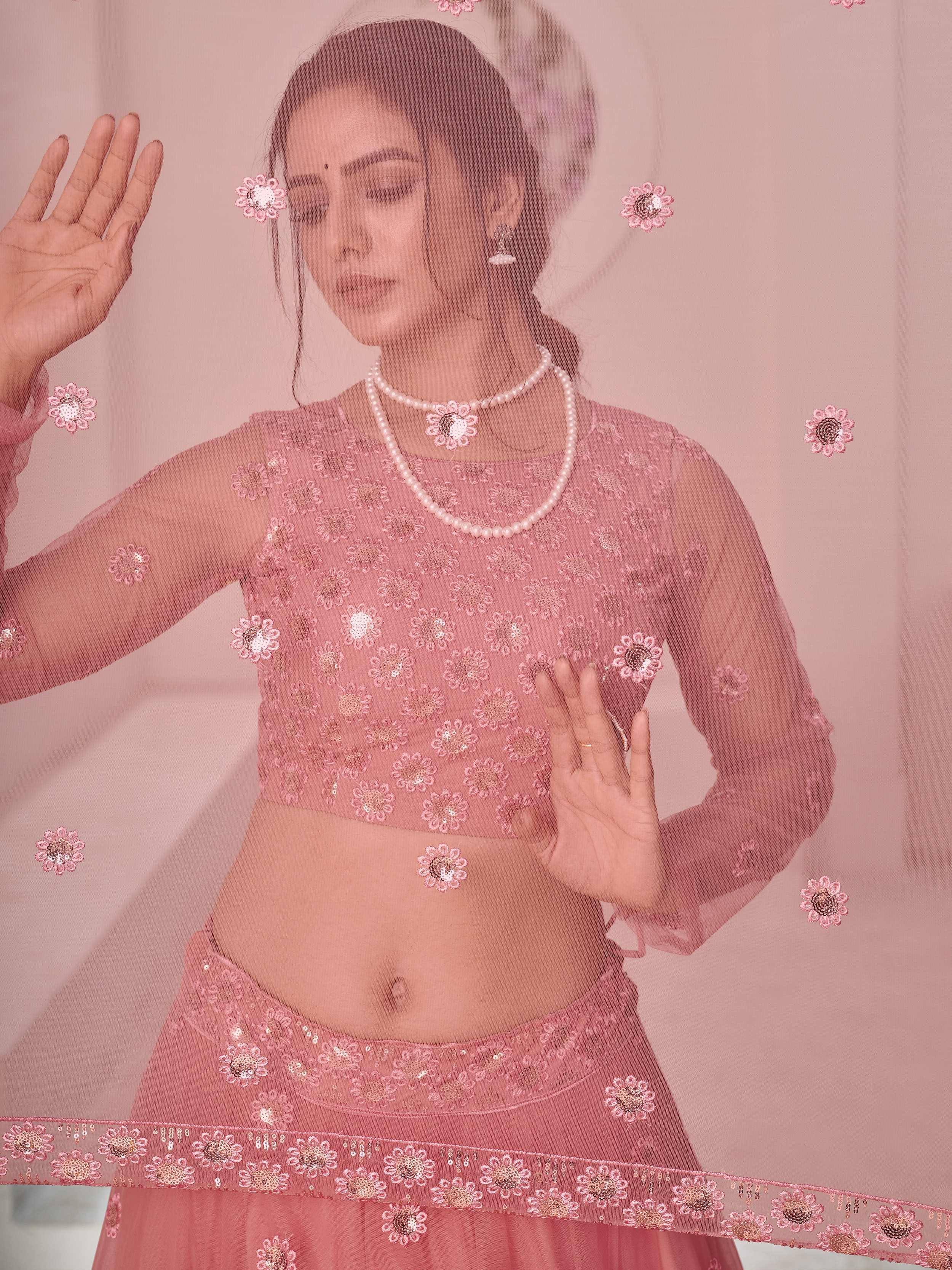 Pink floral embroidered lehenga choli with sheer sleeves and pearl necklace, perfect for Indian ethnic occasions.