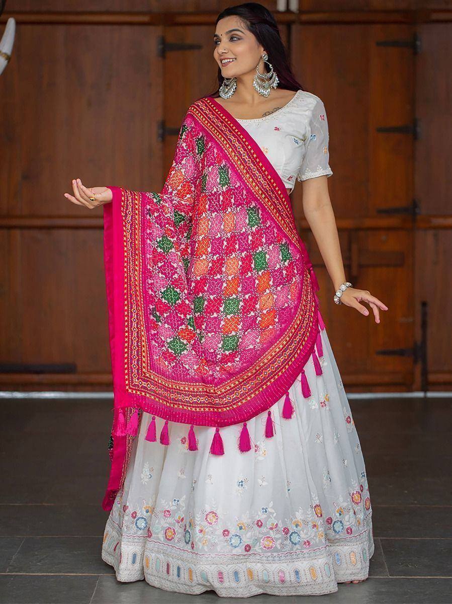 White embroidered lehenga choli with vibrant pink dupatta featuring geometric patterns and tassels
