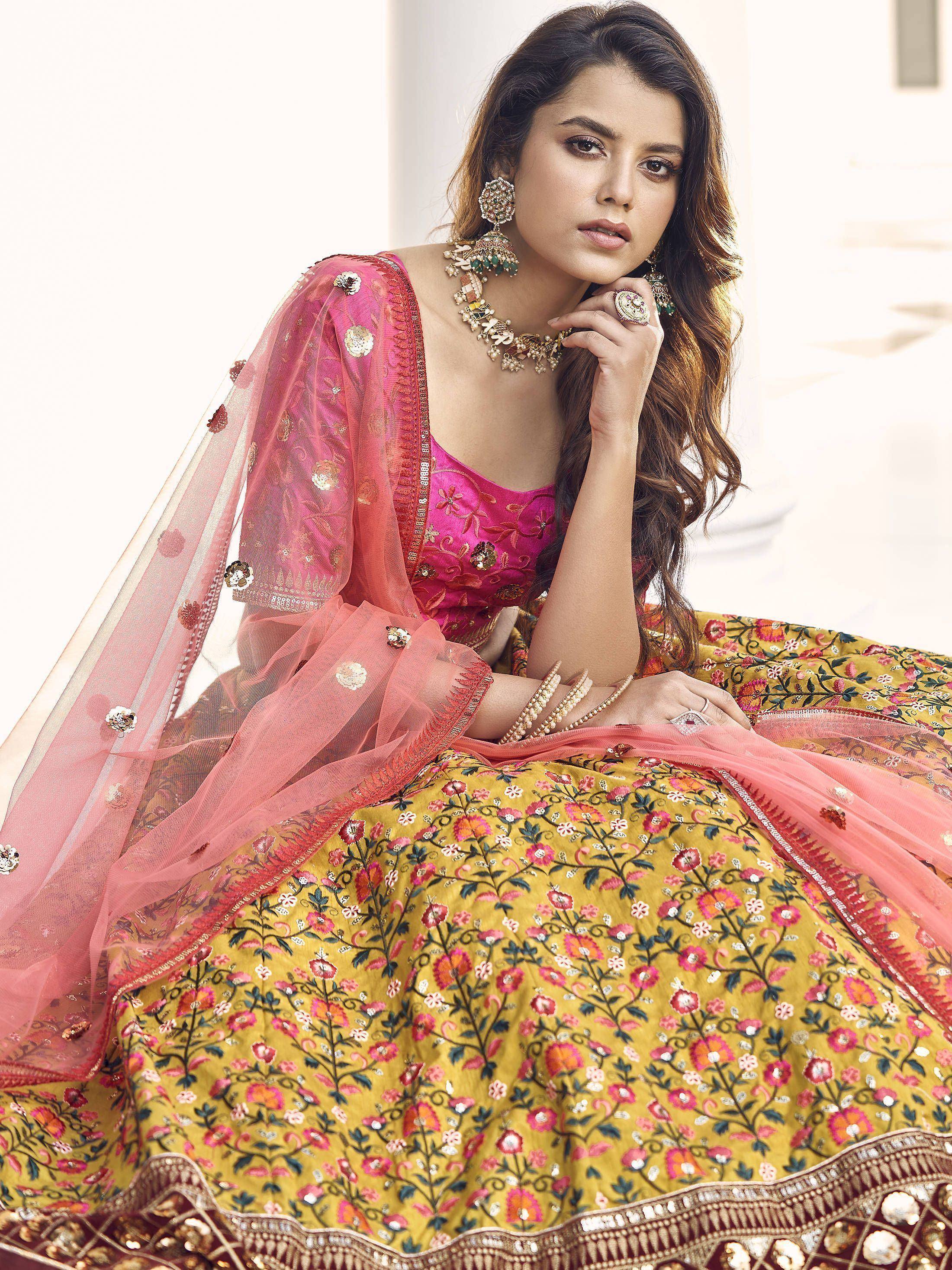 Woman in vibrant yellow floral lehenga choli with pink dupatta, perfect for Indian weddings and festivals