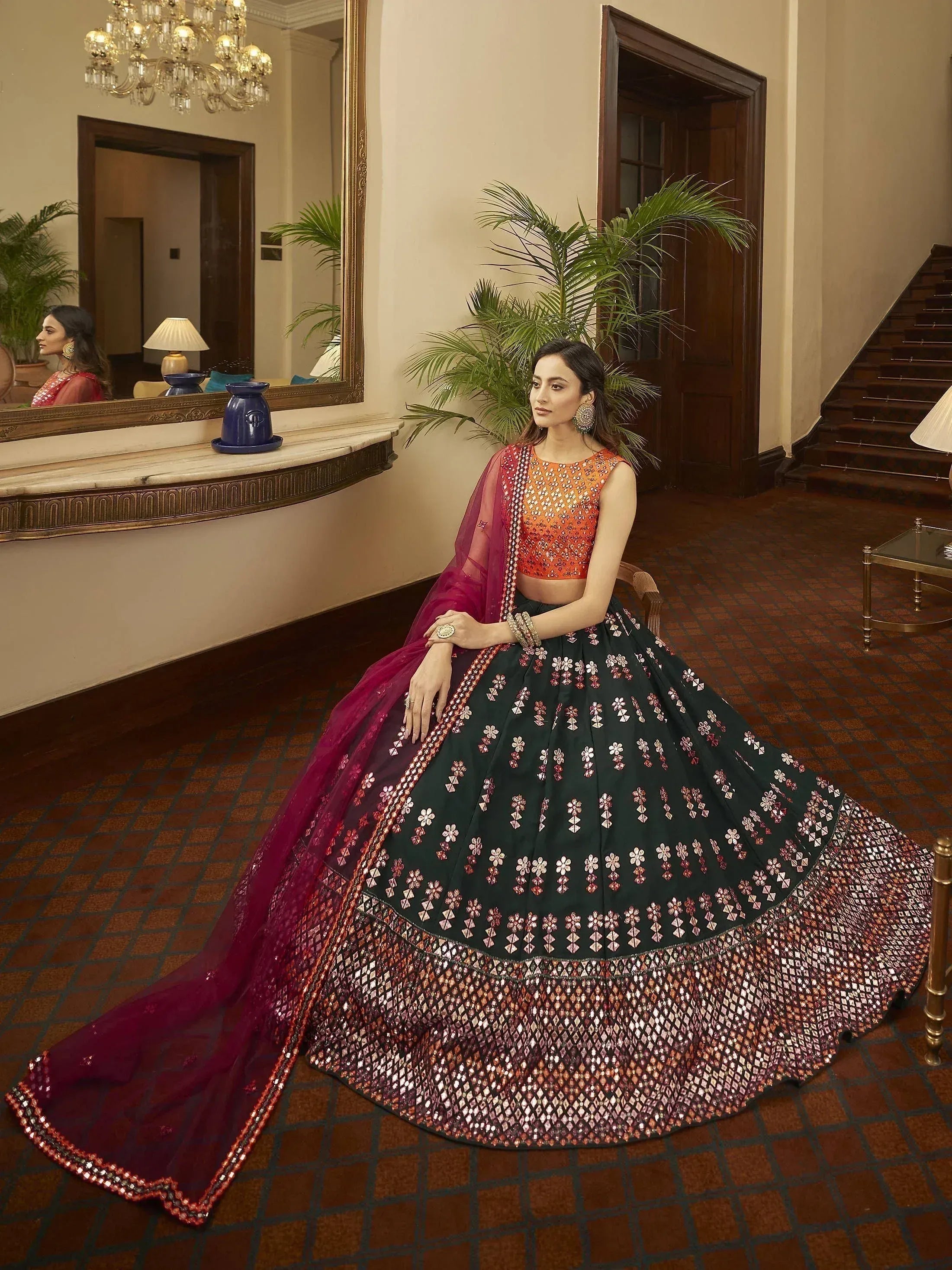 Woman in designer lehenga choli with floral embroidery, orange blouse, and maroon dupatta, elegant ethnic wear