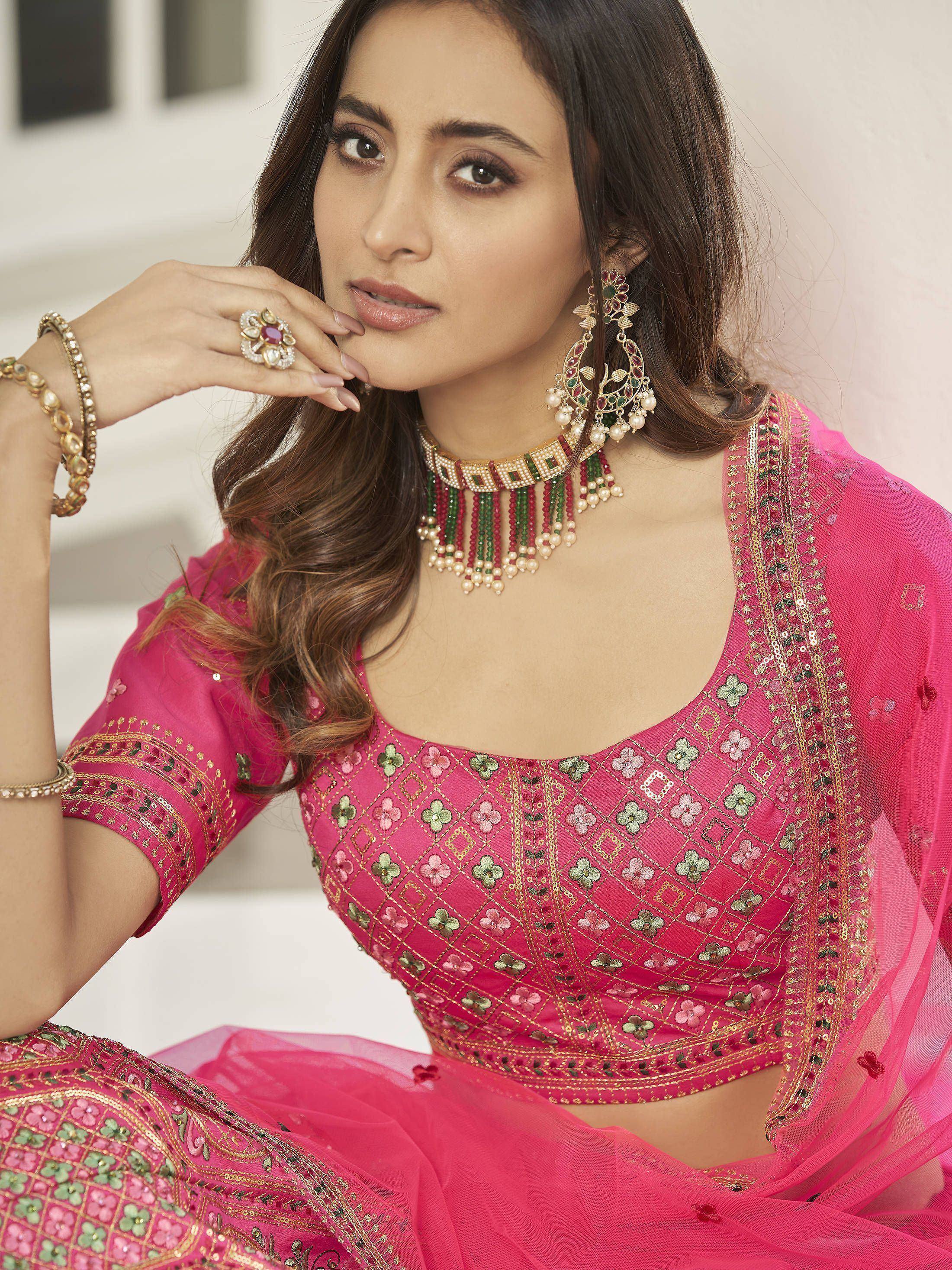 Pink embroidered lehenga choli with floral motifs, gold detailing, and traditional Indian jewelry