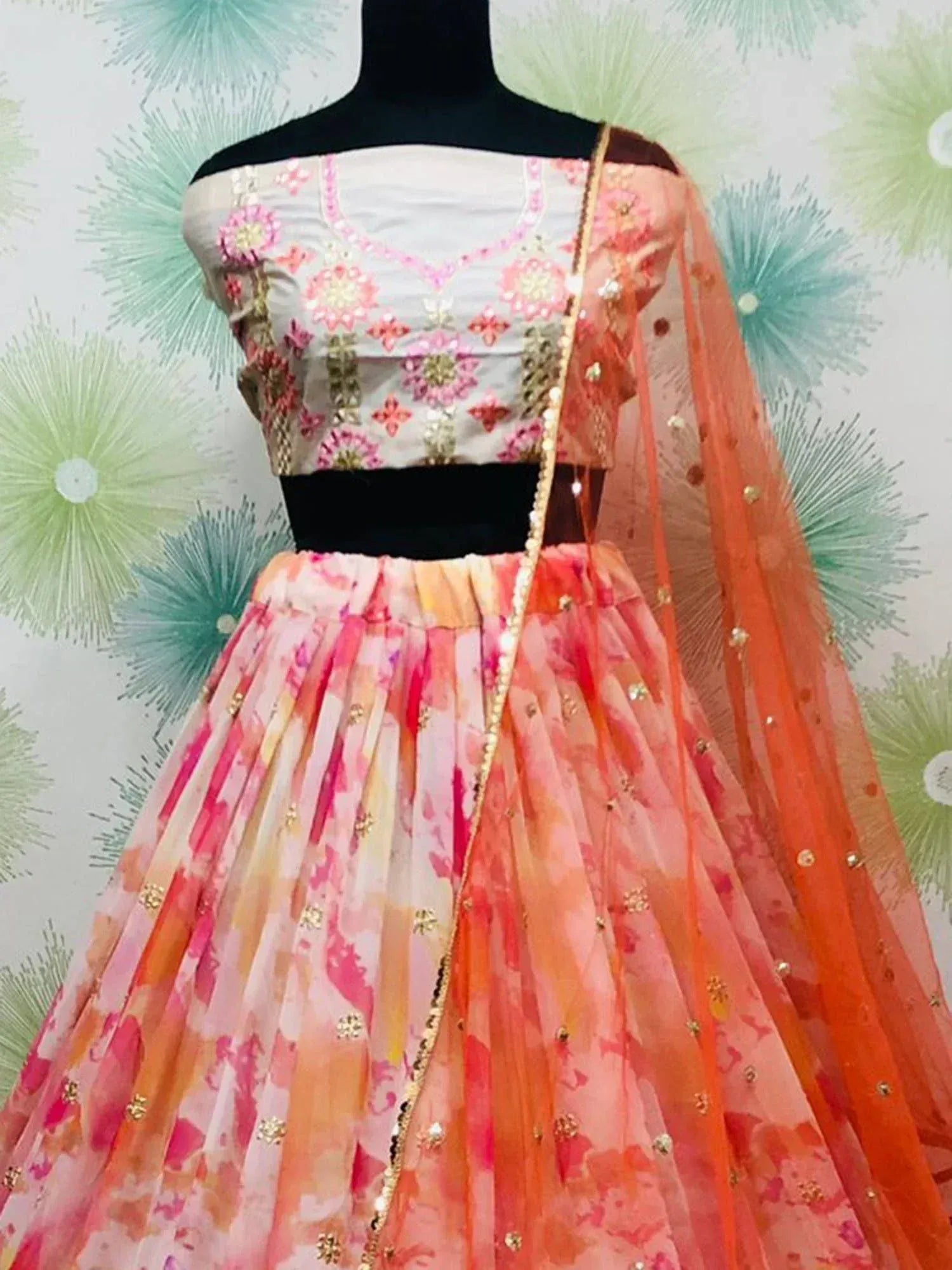 Pink and orange floral lehenga choli with gold embroidery and sheer dupatta, displayed on mannequin