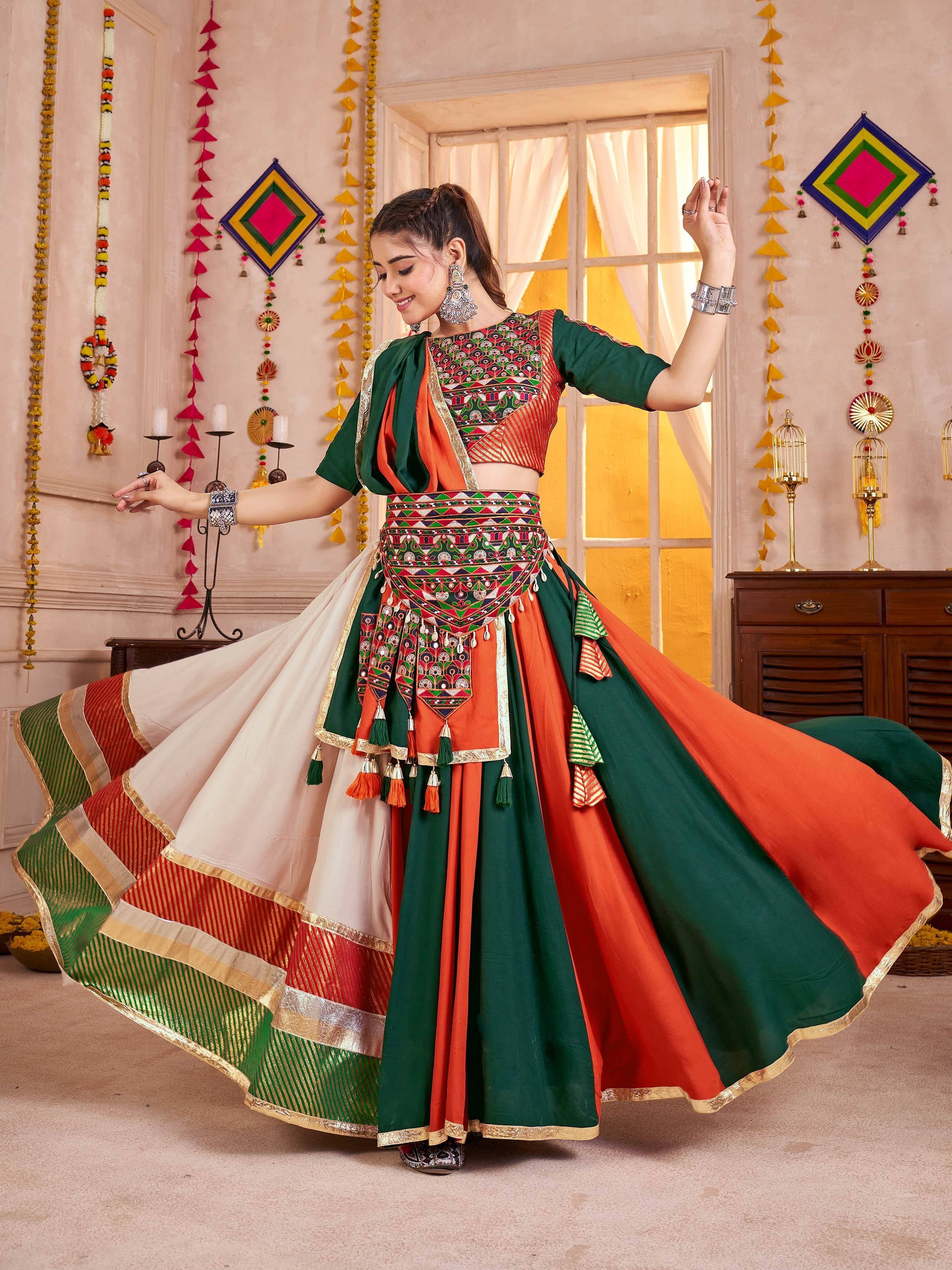 Woman in vibrant green and orange ethnic lehenga choli with intricate embroidery, perfect for festive occasions.