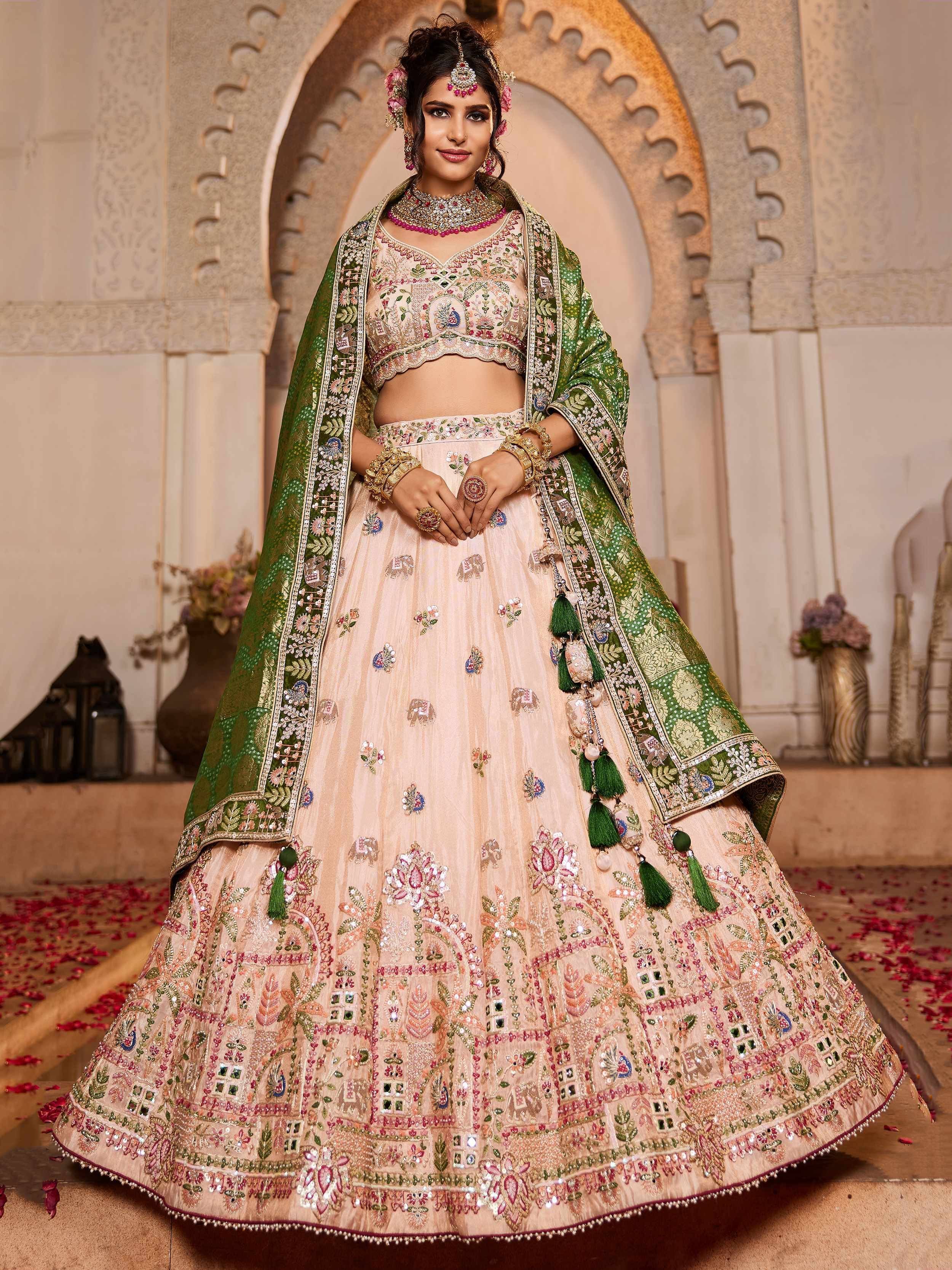 Elegant peach lehenga choli with green dupatta, heavy embroidery, and mirror work for Indian weddings