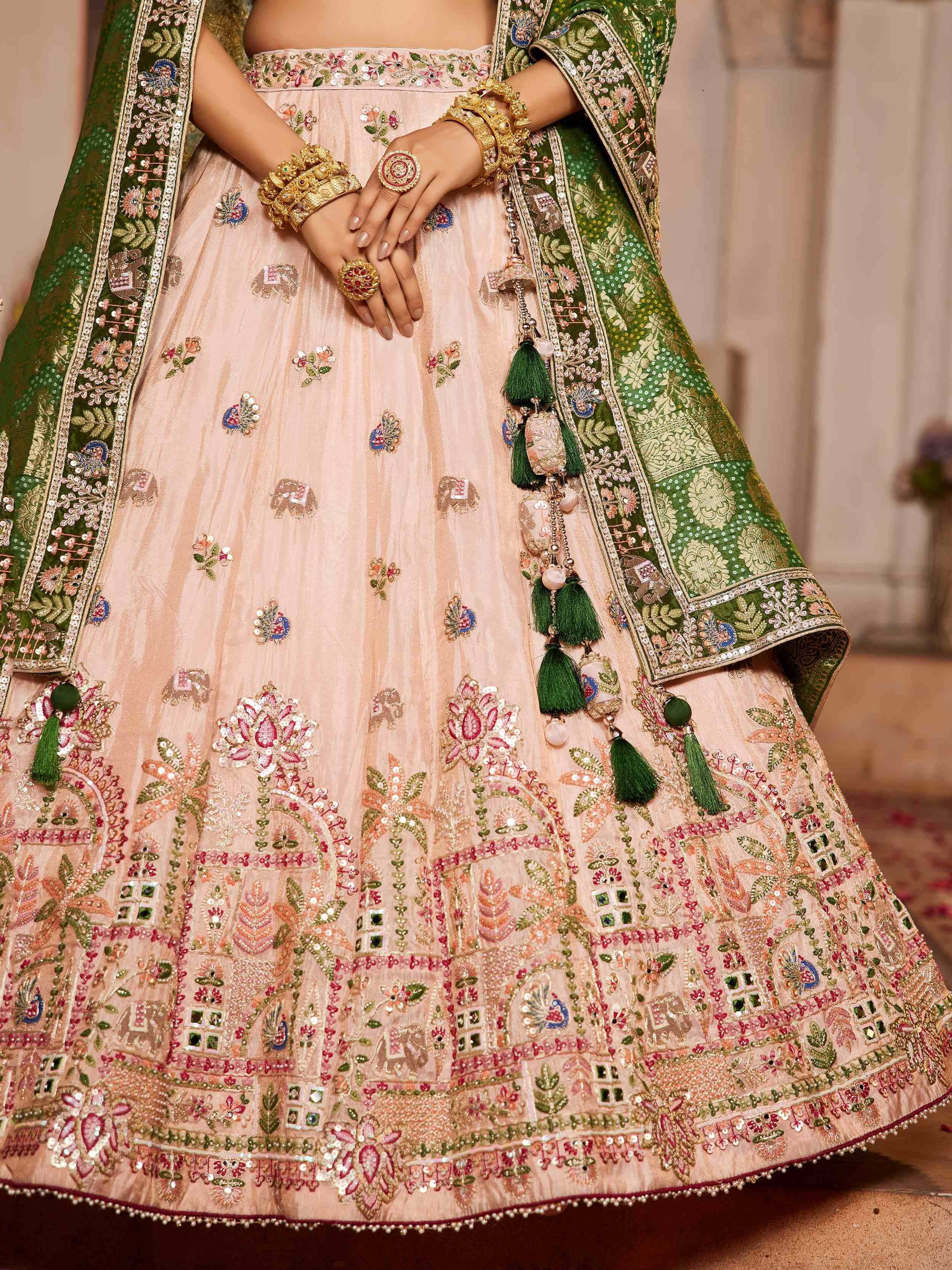 Elegant blush lehenga choli with green dupatta, floral embroidery, and gold jewelry for Indian weddings