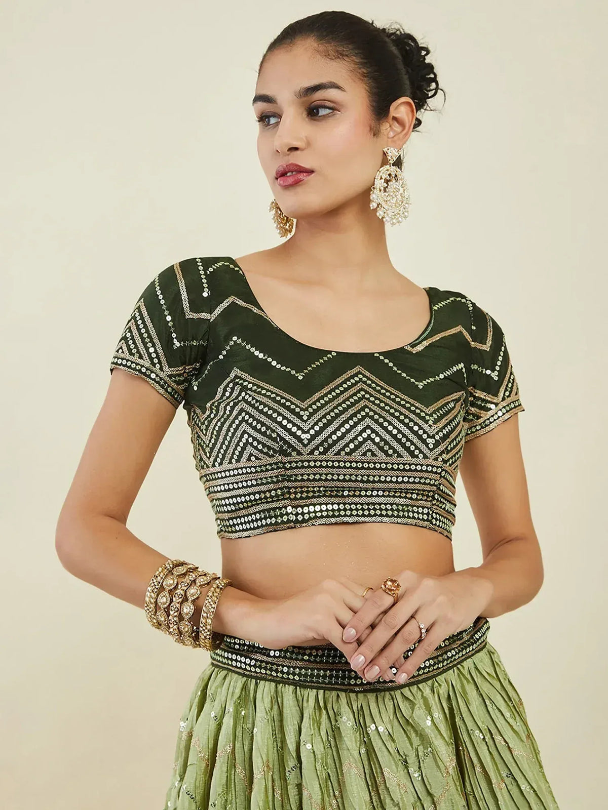Green embroidered lehenga choli with geometric sequin design and matching jewelry