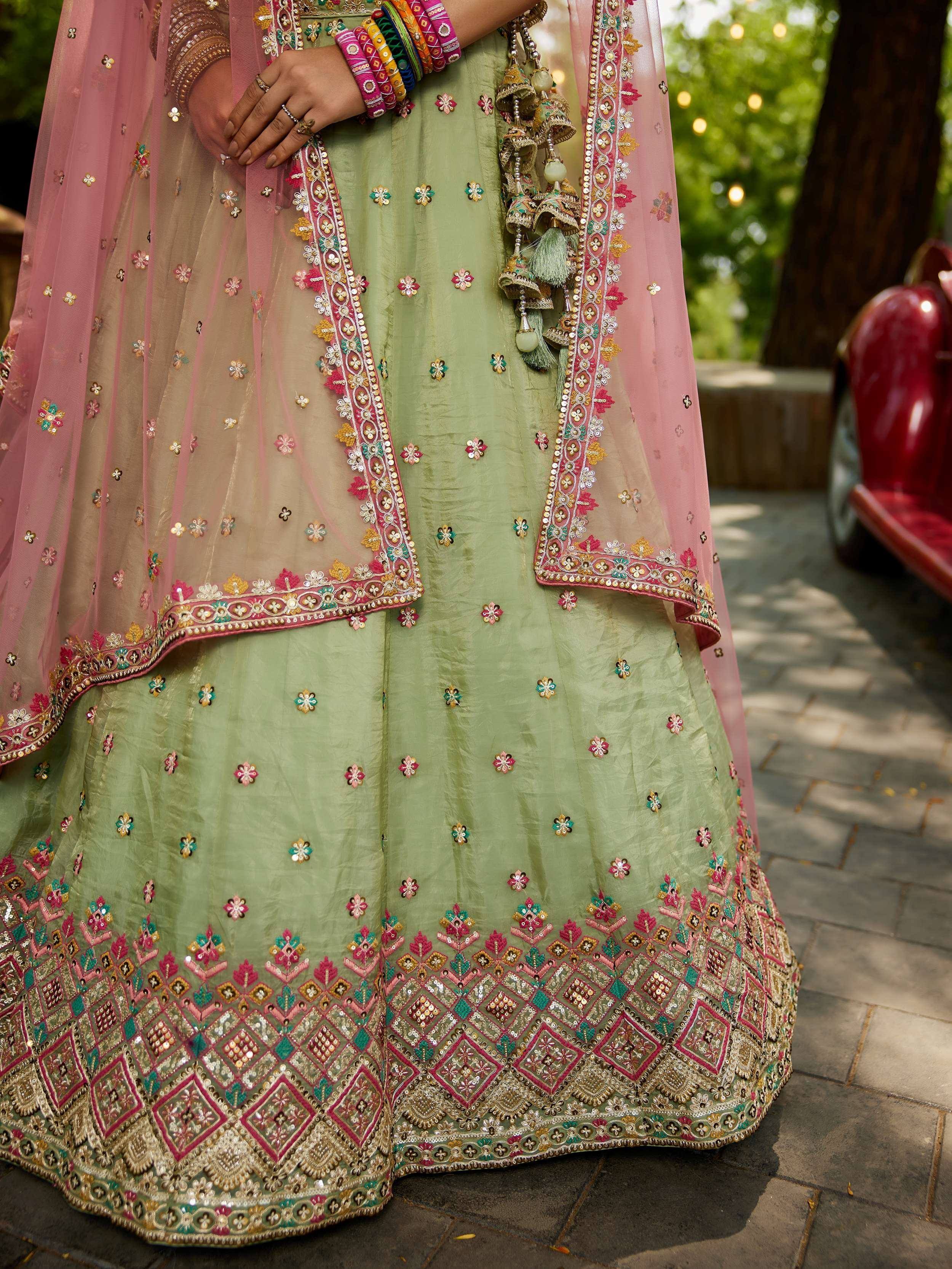 Green embroidered lehenga choli with pink dupatta, floral motifs, and colorful bangles for Indian ethnic wear