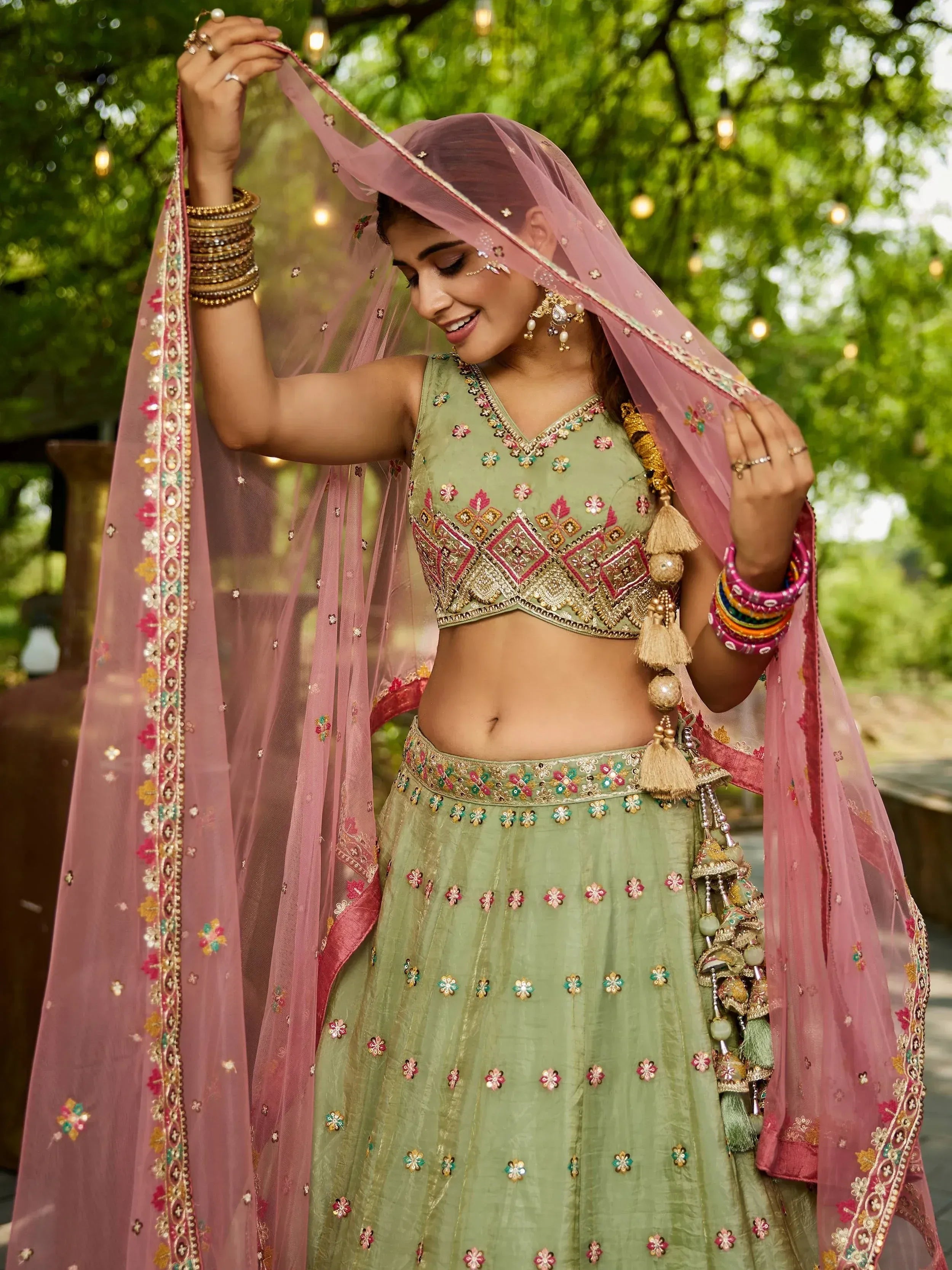 Woman in green embroidered lehenga choli with pink dupatta, traditional Indian ethnic wear