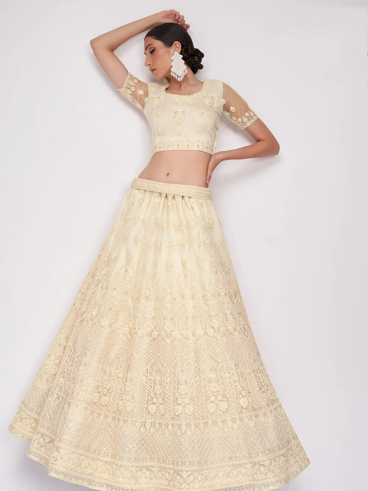 Elegant cream lehenga choli with intricate embroidery and sheer sleeves, perfect for Indian ethnic occasions.