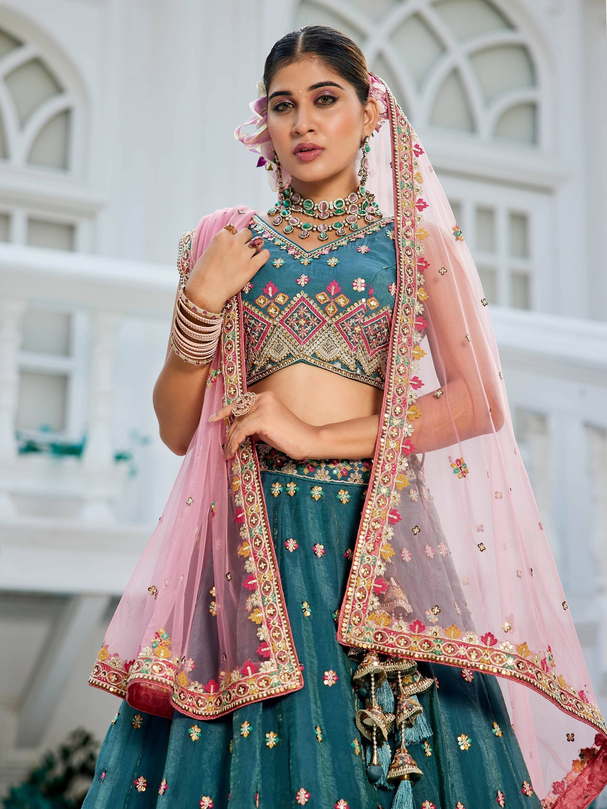 Teal embroidered lehenga choli with pink dupatta, perfect for Indian weddings and festive occasions.