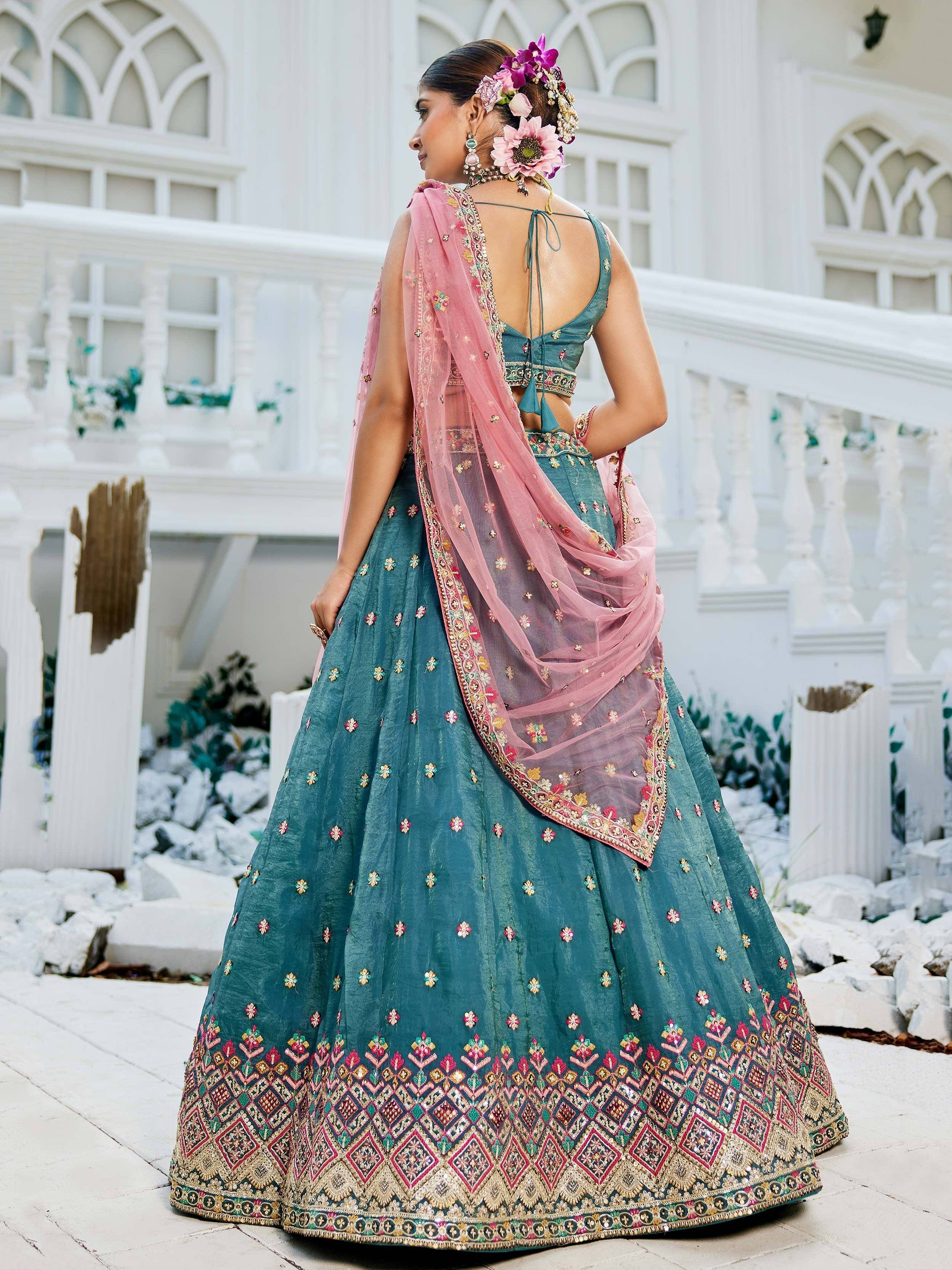 Teal embroidered lehenga choli with pink dupatta, floral hair accessories, and backless blouse for Indian ethnic wear