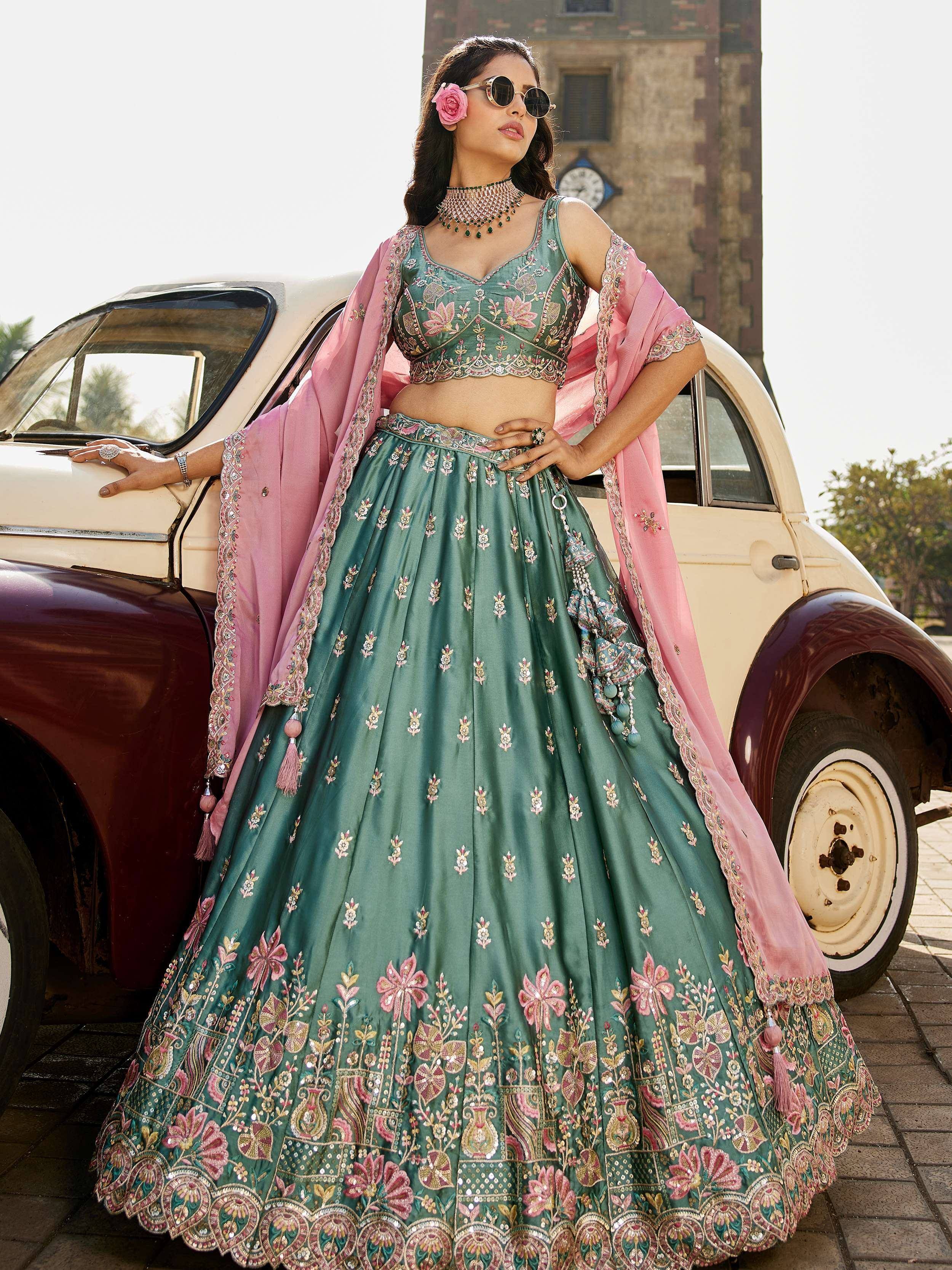 Green embroidered lehenga choli with pink dupatta, styled with sunglasses beside vintage car