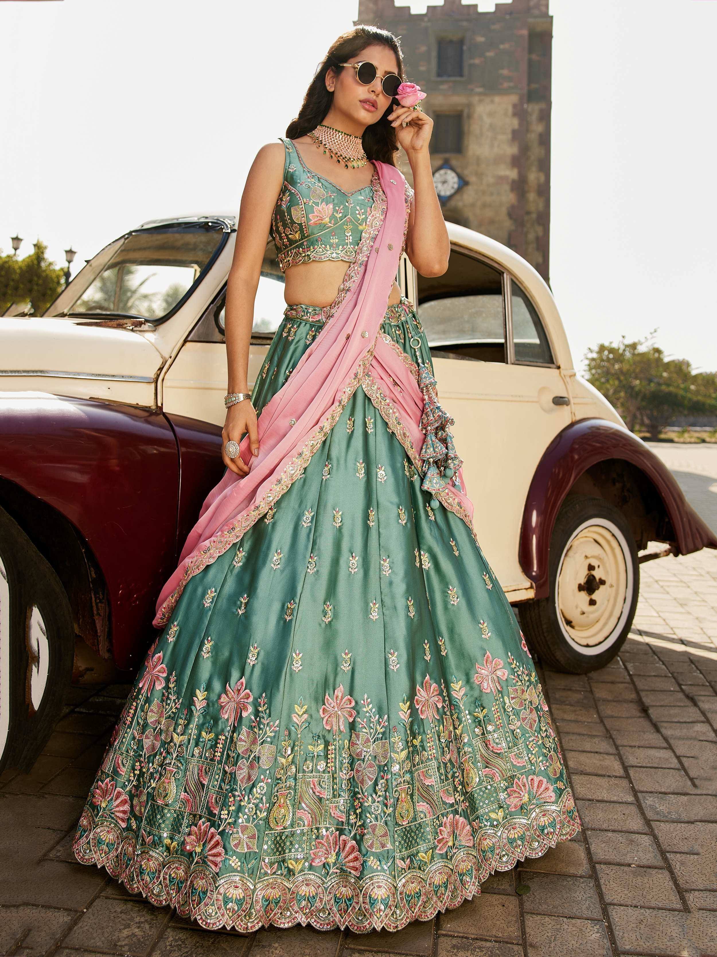 Green floral embroidered lehenga choli with pink dupatta, styled with vintage car and castle backdrop