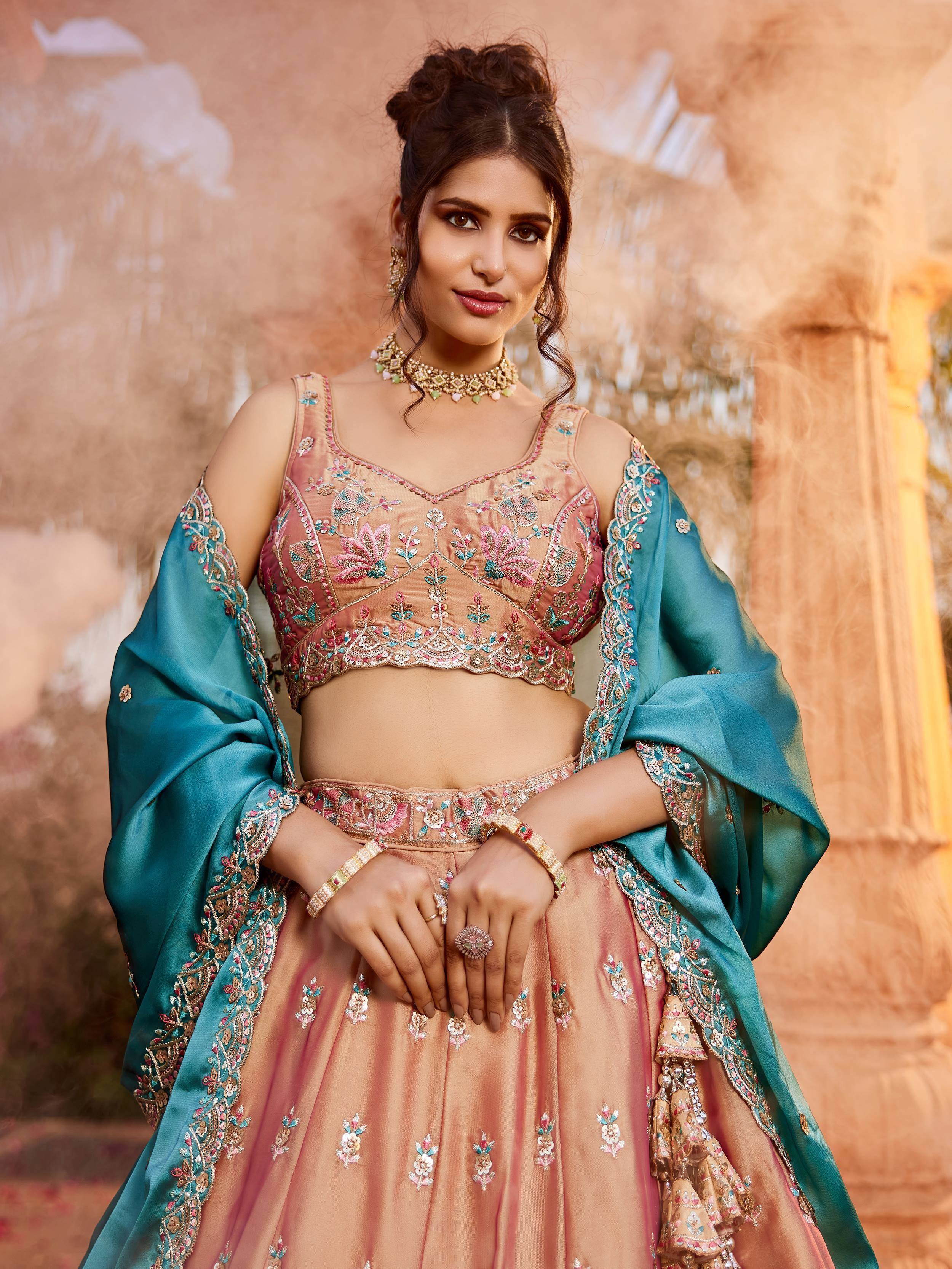 Elegant peach lehenga choli with floral embroidery and teal dupatta, perfect for Indian weddings and festive occasions.