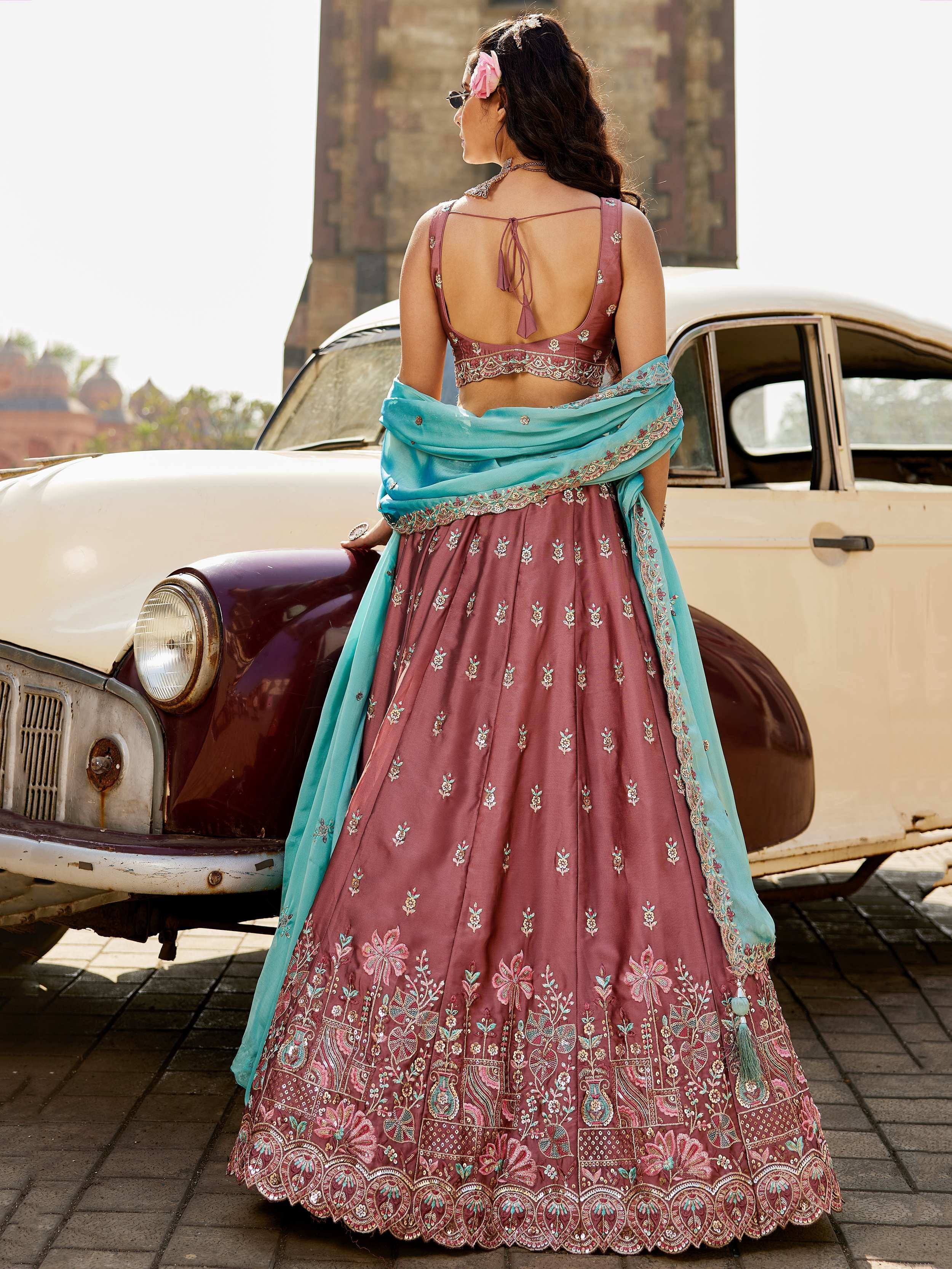 Woman in maroon embroidered lehenga choli with blue dupatta, standing by vintage car, Indian ethnic wear