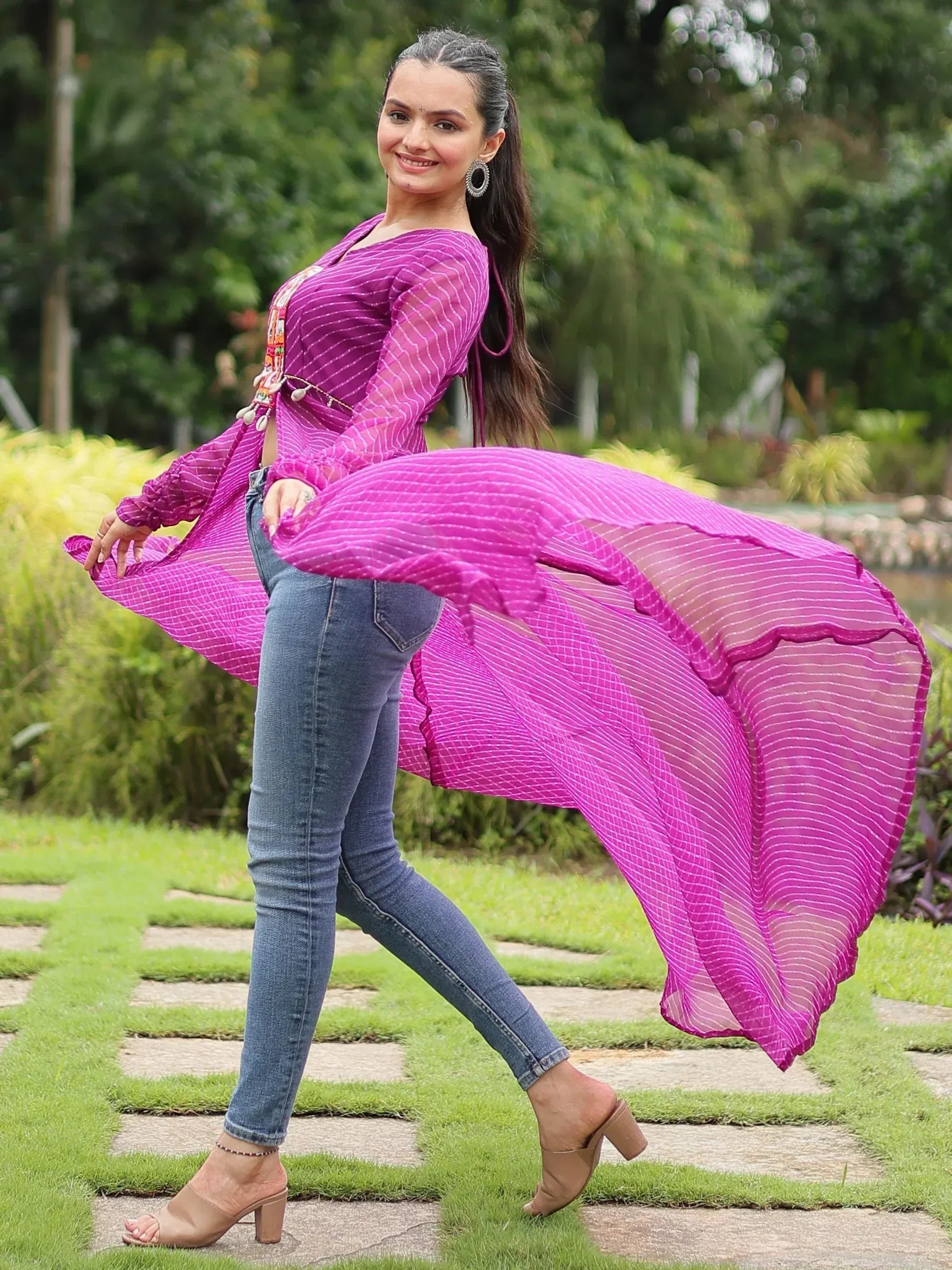 Woman in vibrant purple striped ethnic top with flared sleeves, paired with jeans, outdoors