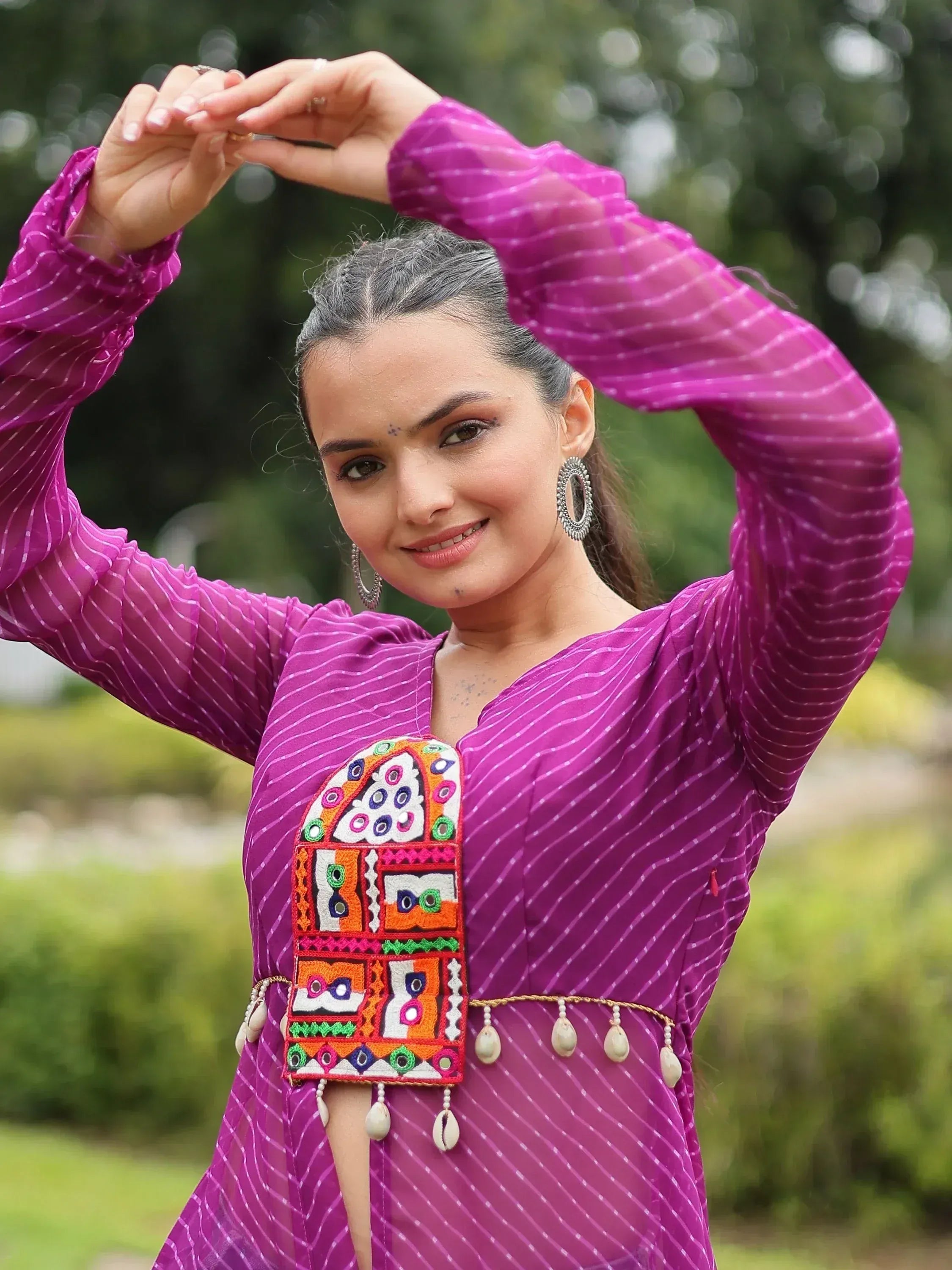 Woman in vibrant purple ethnic gown with colorful mirror embroidery and shell belt, perfect for Indian festive wear.