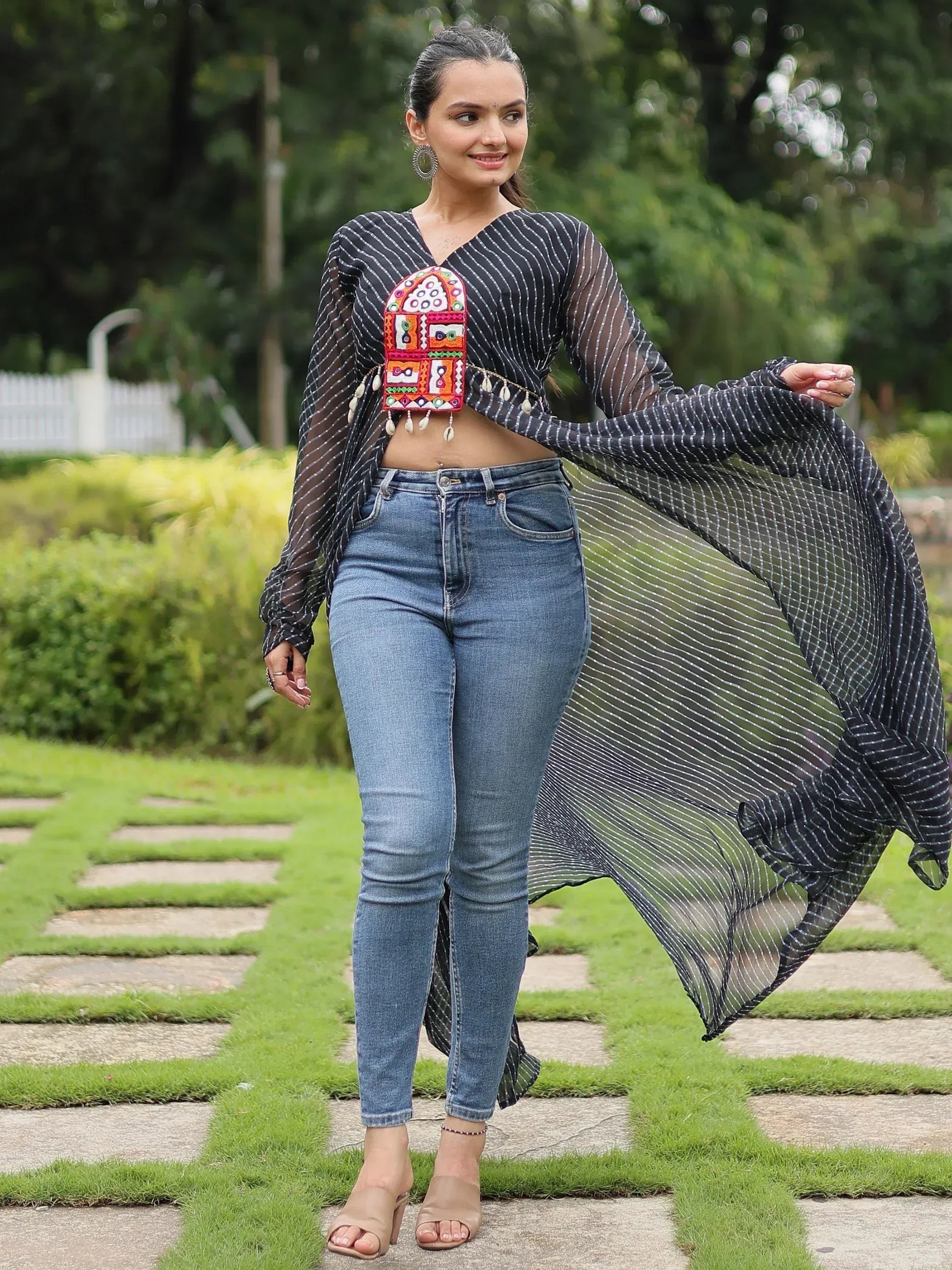 Black striped sheer ethnic top with colorful embroidery, paired with blue jeans for a fusion look
