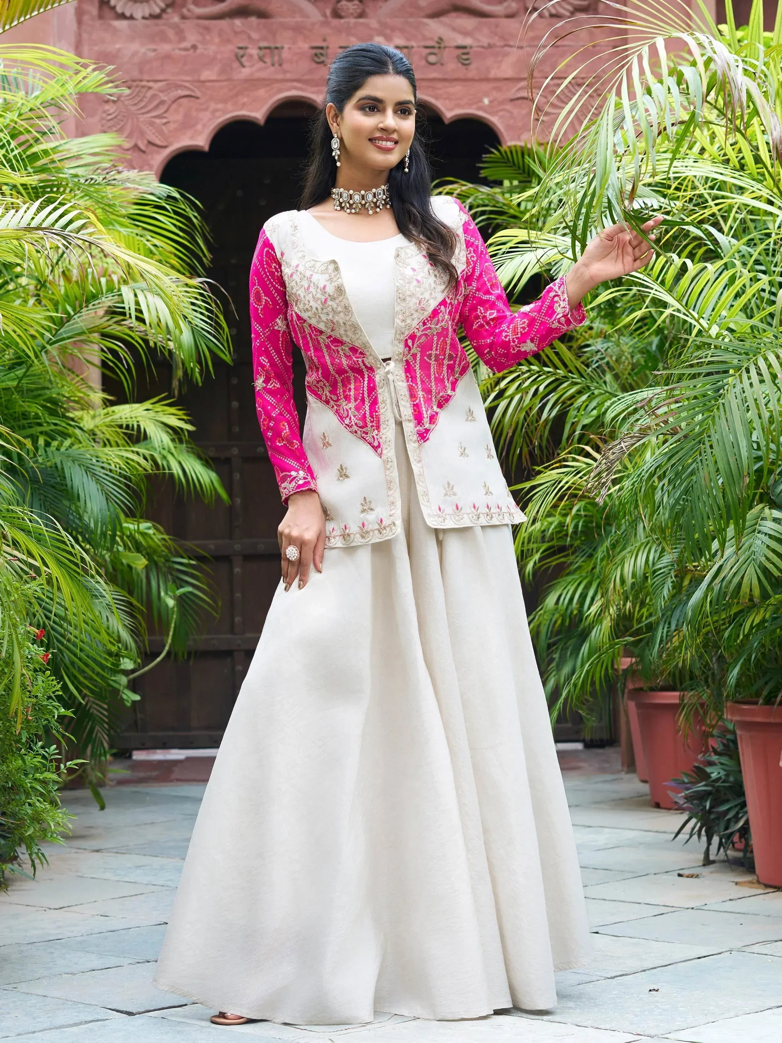 Woman in elegant white and pink embroidered ethnic gown with traditional jewelry, perfect for Indian occasions