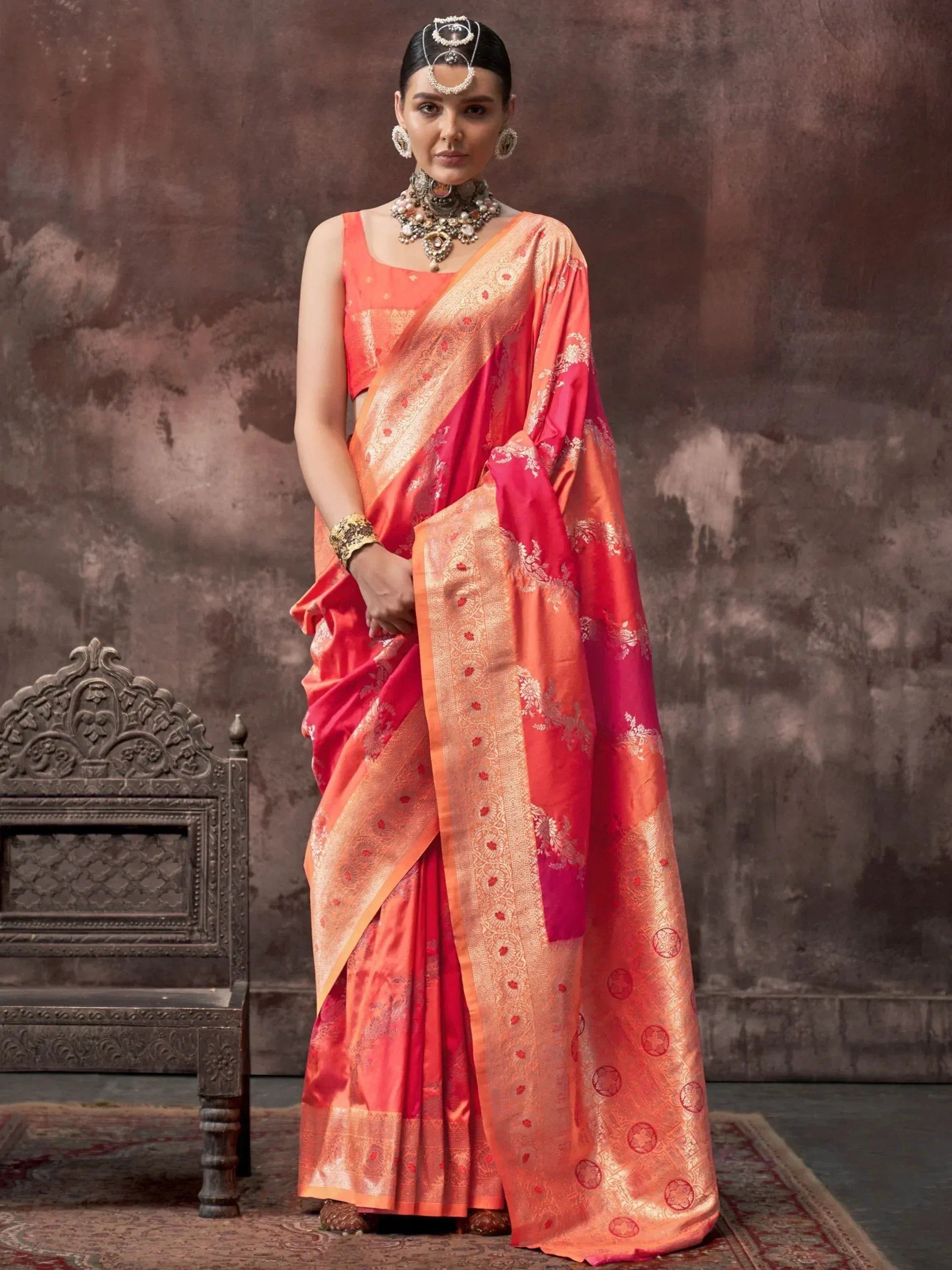 Woman in vibrant coral and gold designer saree with intricate embroidery, traditional Indian ethnic wear