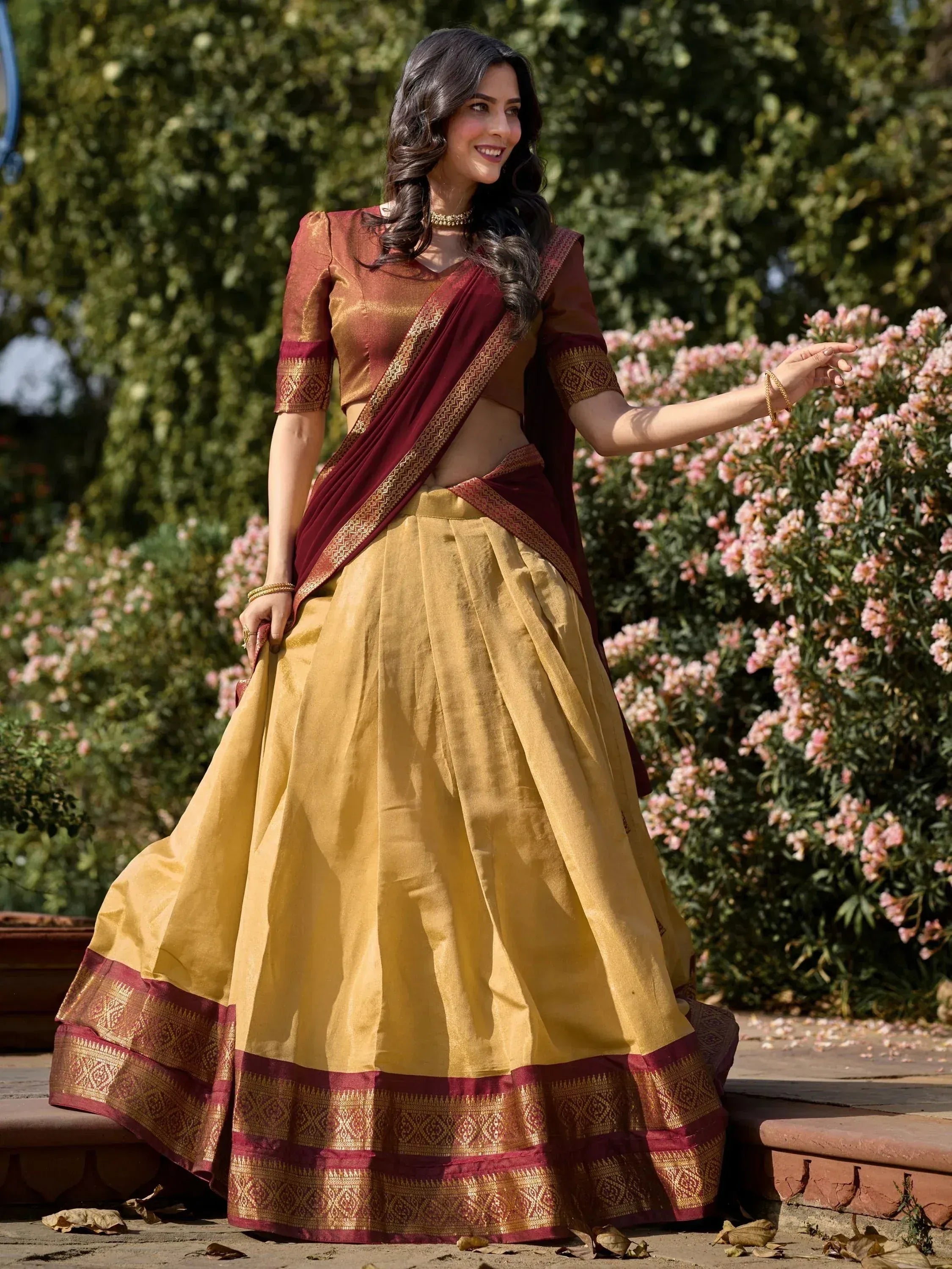 Woman in maroon and gold designer lehenga choli with intricate border, perfect for Indian ethnic wear occasions