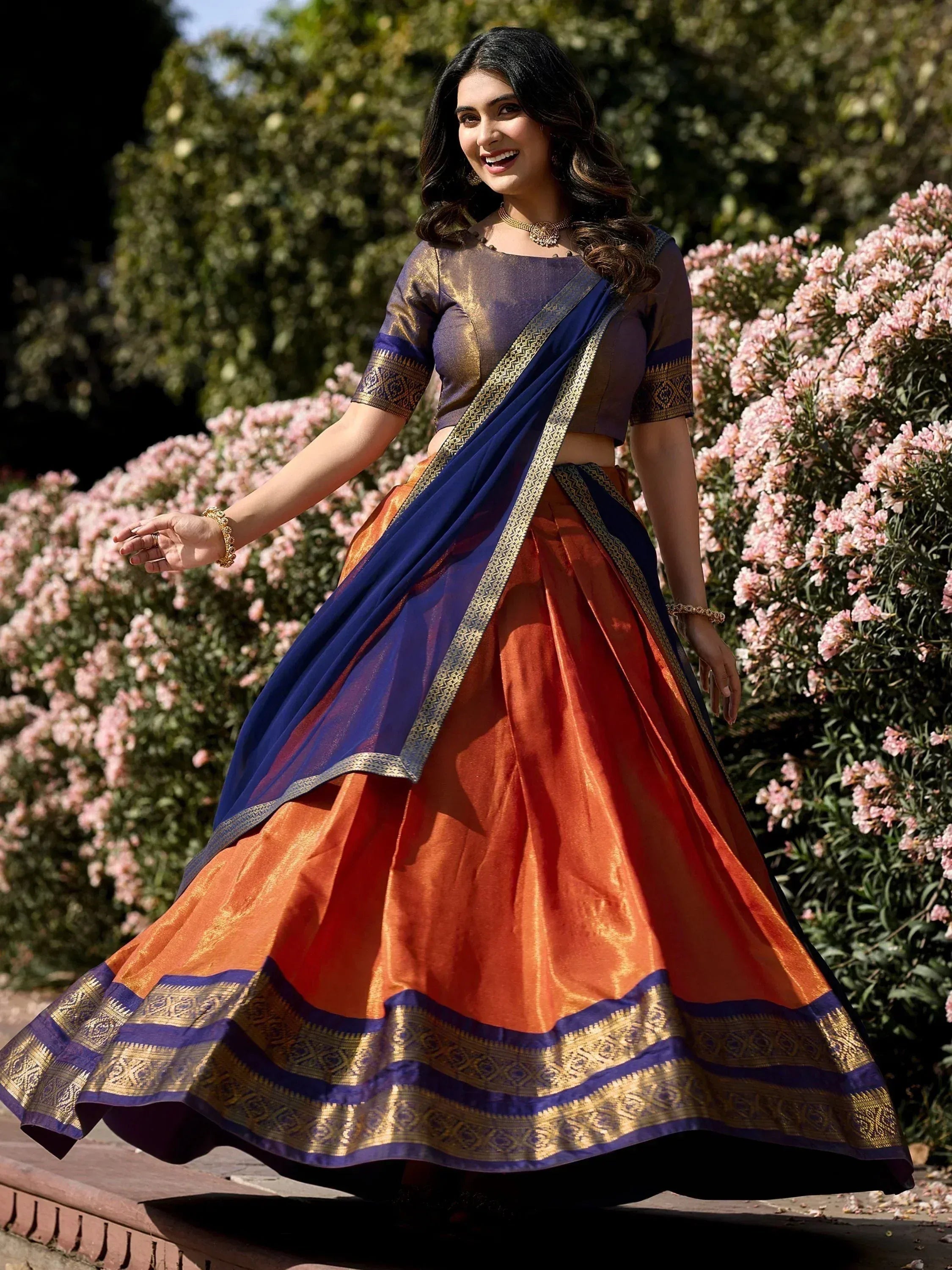 Woman in vibrant orange and blue lehenga choli with gold embroidery, perfect for Indian ethnic occasions