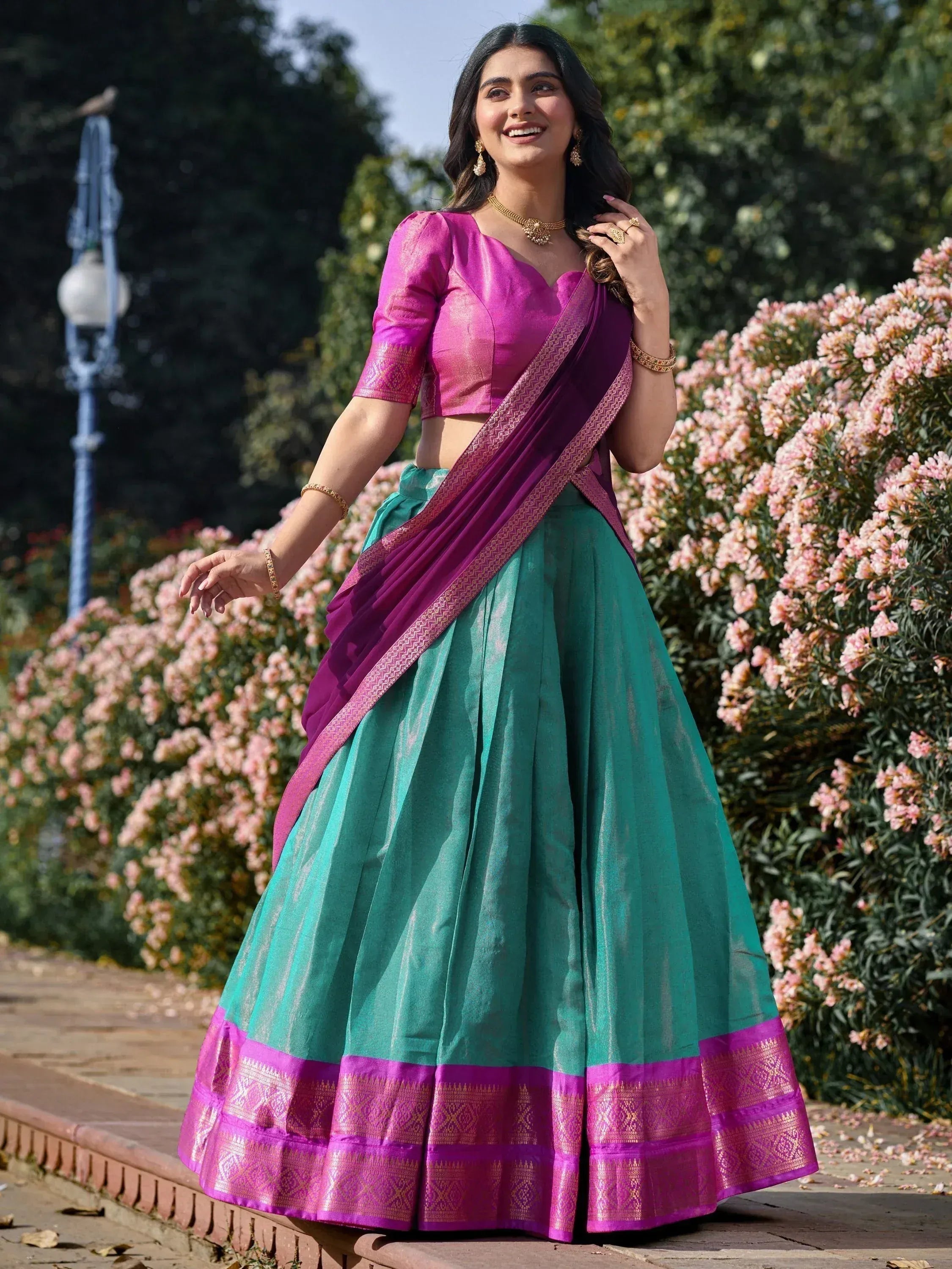 Woman in vibrant pink and teal lehenga choli with gold embroidery, perfect for Indian ethnic occasions
