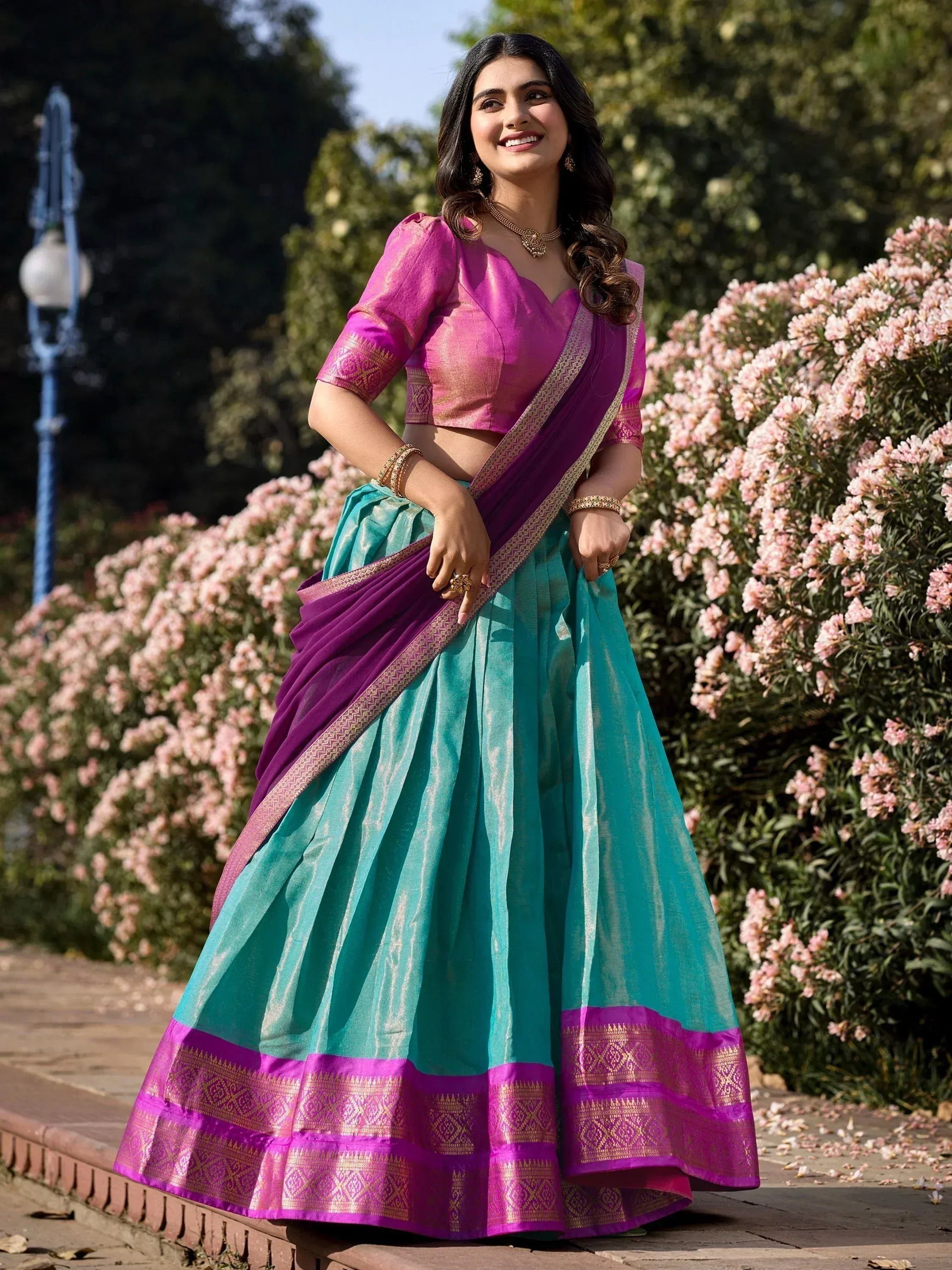 Woman in vibrant purple and teal lehenga choli with gold border, perfect for Indian ethnic occasions