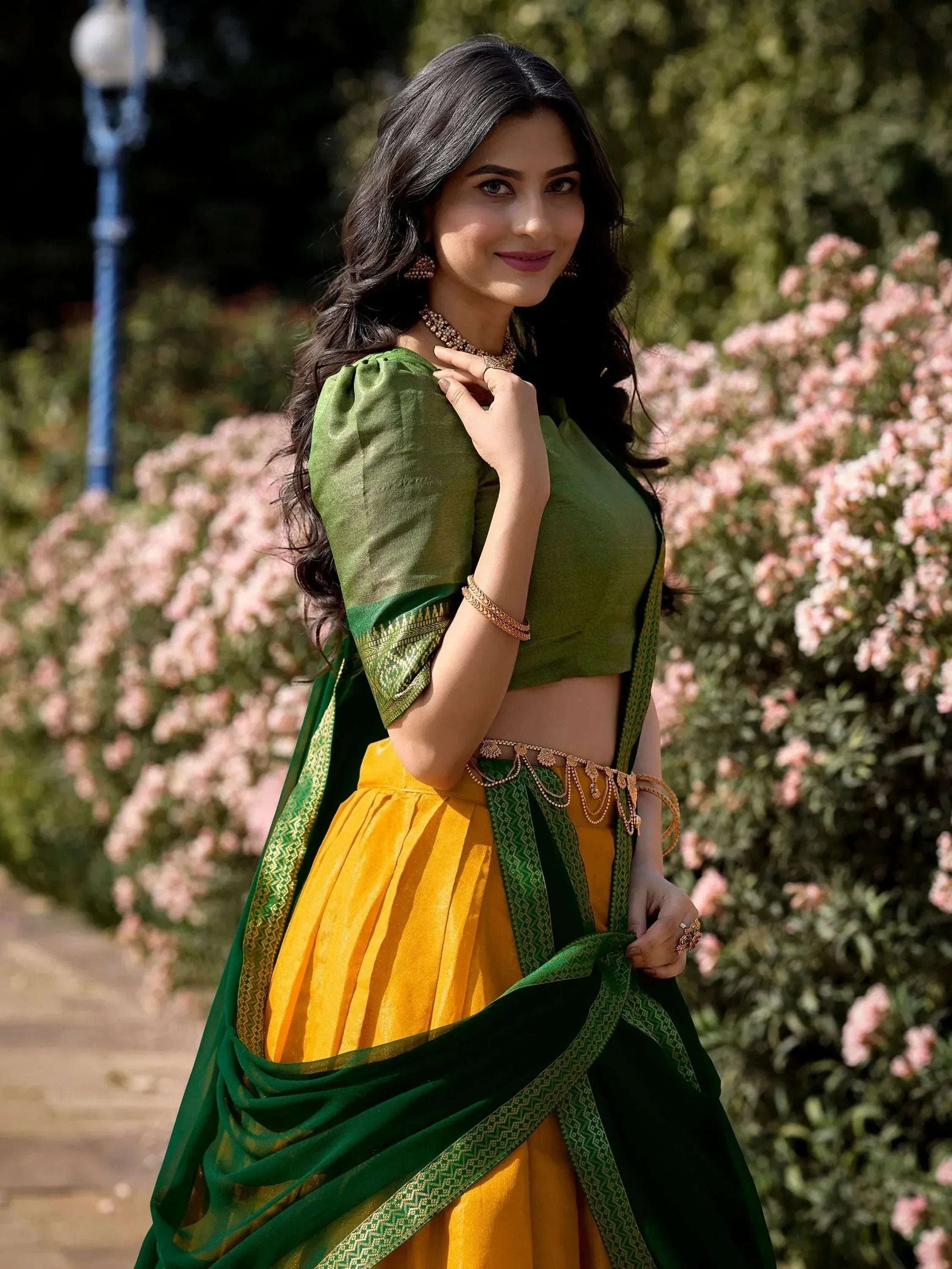 Green and yellow ethnic lehenga choli with gold embroidery, styled with traditional jewelry