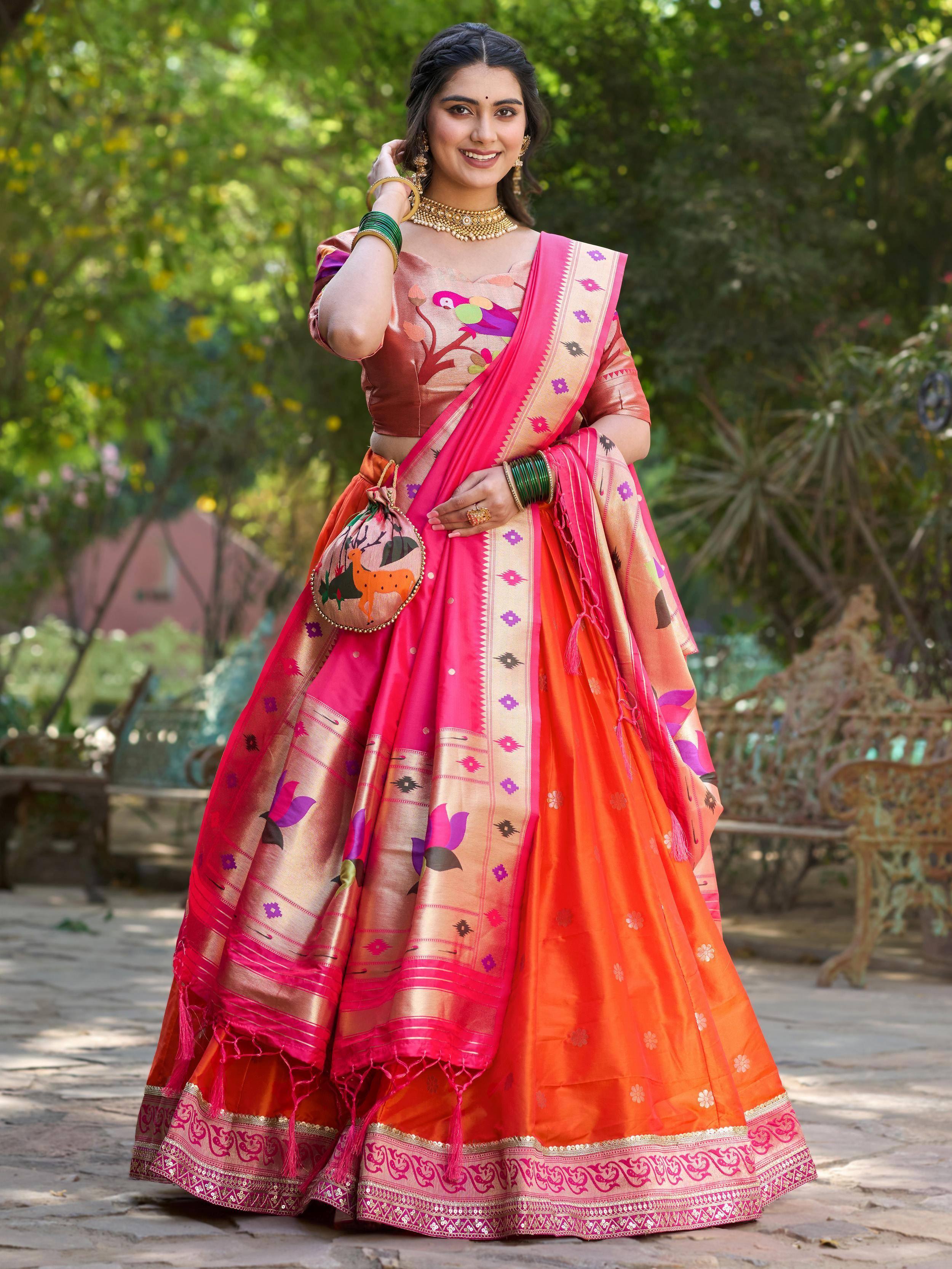 Woman in vibrant pink and orange designer lehenga choli with floral and bird motifs, perfect for Indian ethnic occasions.