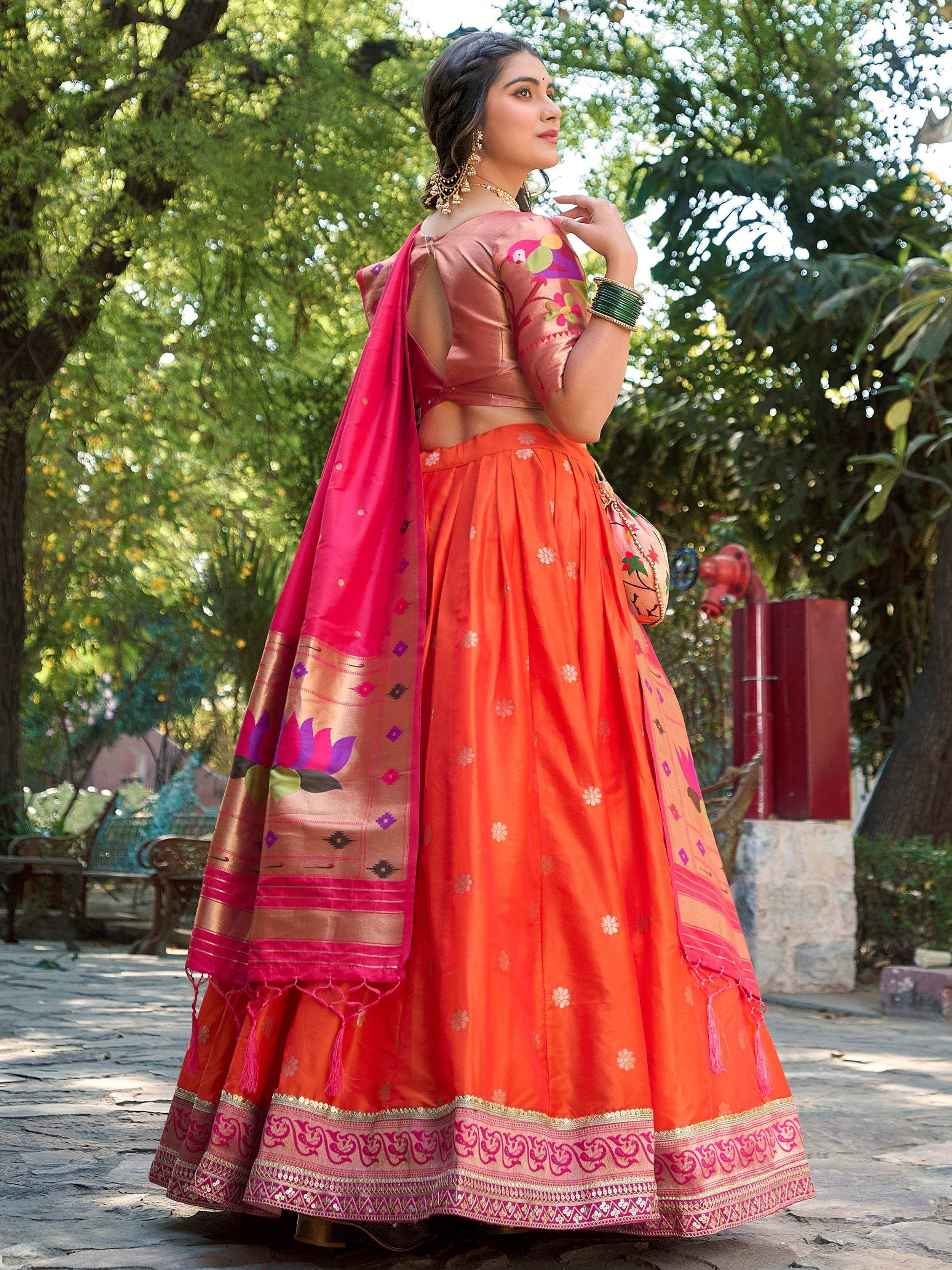 Woman in vibrant orange lehenga choli with floral embroidery and pink dupatta, perfect for Indian ethnic occasions.