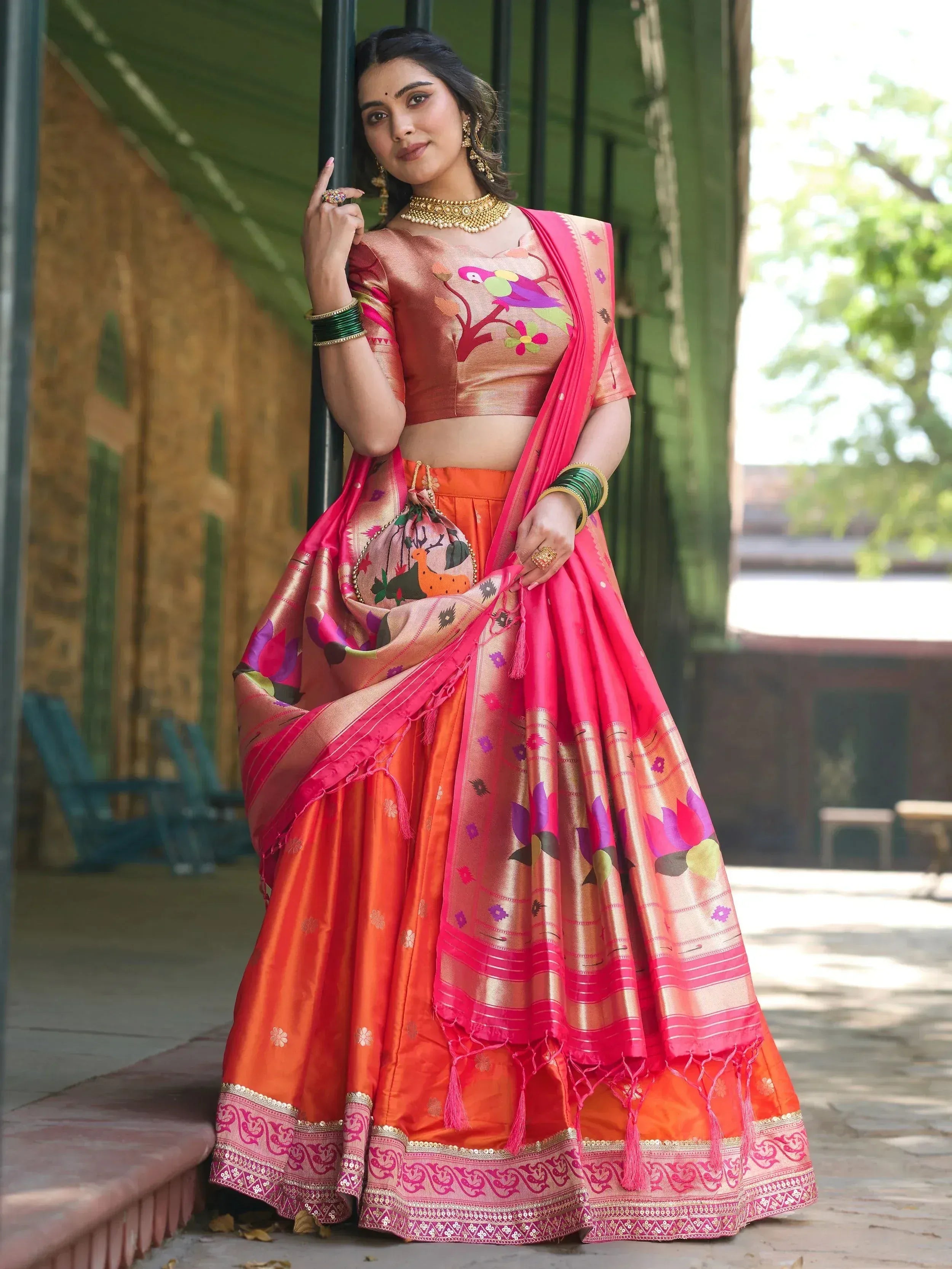 Vibrant orange and pink designer lehenga choli with floral and bird embroidery, perfect for Indian ethnic wear.