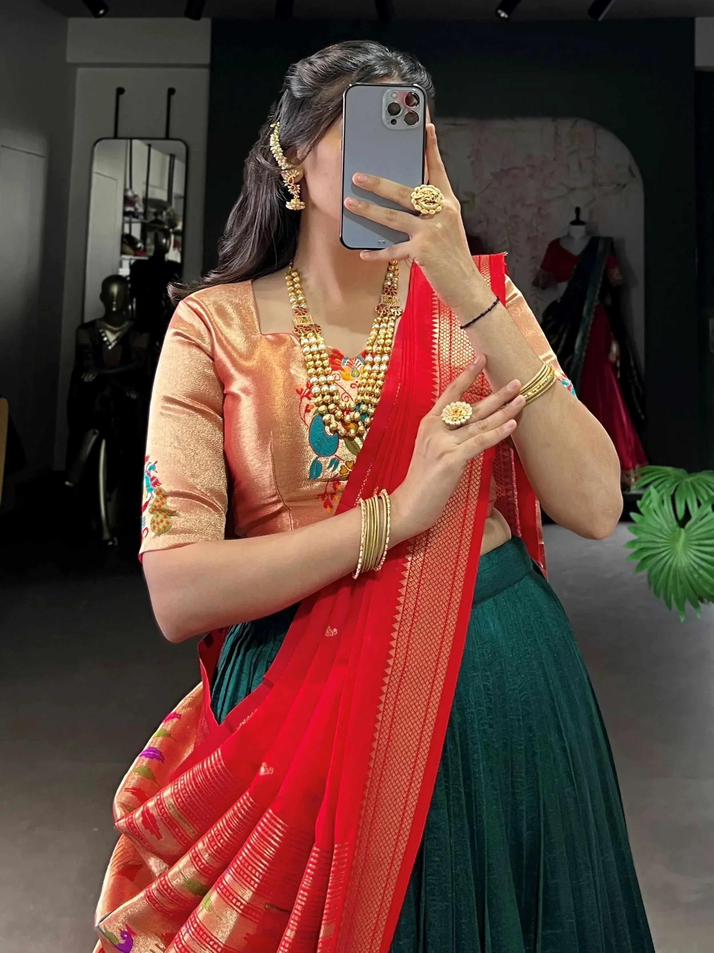 Woman in traditional Indian ethnic wear with embroidered blouse, red saree, and gold jewelry